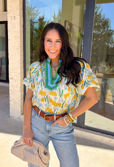 Bright, happy, and made for spring days, this cream short sleeve top by Entro is full of charming details. Featuring a colorful floral print with pops of yellow, blue, and green, it brings an easy burst of color to your look. The green and blue trim along the top adds contrast, while the blue scalloped trim gives it a sweet, polished finish. Puff sleeves complete the look with a soft, feminine touch, making this top perfect for sunny days ahead.