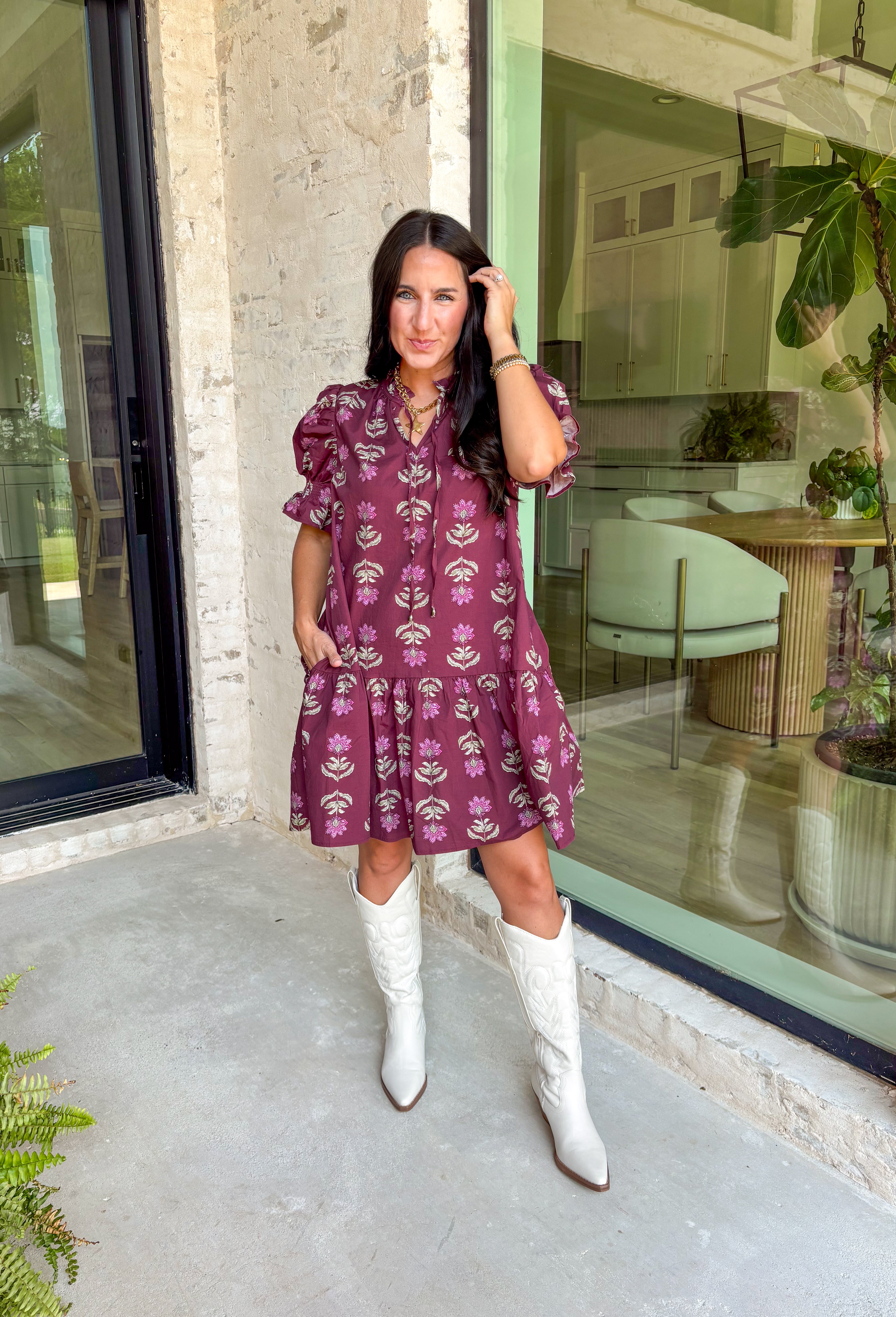 Rich fall tones meet sweet, feminine details in this burgundy mini dress. Covered in a soft pink floral print, it features a smocked finish for a flattering fit and short puff sleeves for just the right amount of charm. The ruffle-edged self-tie v-neckline adds a romantic touch, while side pockets keep it as practical as it is pretty. Made with a cotton blend for comfort and ease, this dress is your go-to for any special occasion!