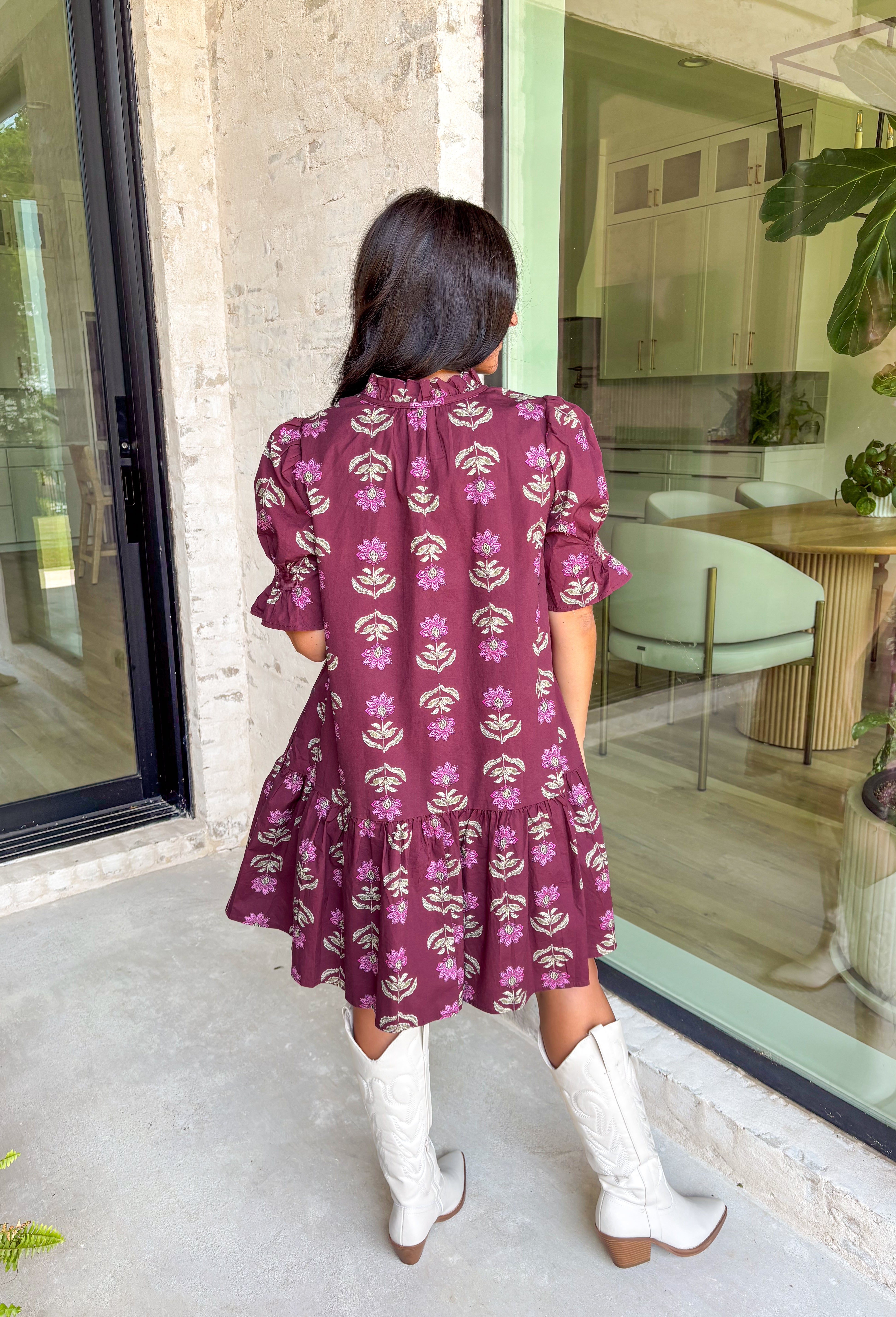 Rich fall tones meet sweet, feminine details in this burgundy mini dress. Covered in a soft pink floral print, it features a smocked finish for a flattering fit and short puff sleeves for just the right amount of charm. The ruffle-edged self-tie v-neckline adds a romantic touch, while side pockets keep it as practical as it is pretty. Made with a cotton blend for comfort and ease, this dress is your go-to for any special occasion!