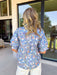 Soft, dreamy, and made for sunny spring days — this faded blue top features a delicate washed floral print in peach, airy blues, and light purple tones that feel effortlessly fresh. The vintage-inspired finish gives it that perfectly worn-in charm while still feeling polished and feminine. Light purple scalloped trim runs along the front for the sweetest pop of contrast, while subtle smocking adds texture and flattering shape. 
