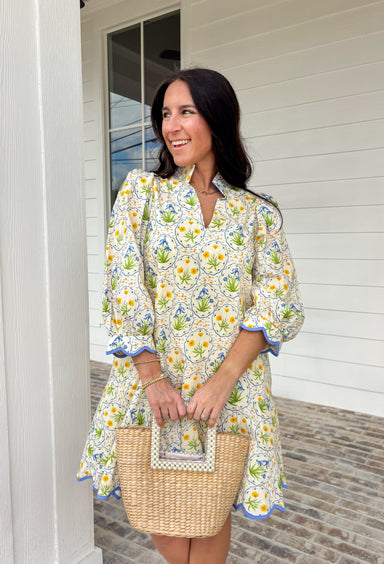 Fresh, cheerful, and made for spring days, this off-white dress by Entro is full of easy charm. Featuring a blue and yellow botanical floral print, it feels bright and breezy for the season. The split neckline adds a flattering touch, while the 3/4 puff sleeves bring soft volume. Scallop accent trim at the cuffs and hem gives it extra detail, and side pockets (because we love a functional moment) make it just as practical as it is pretty. 
