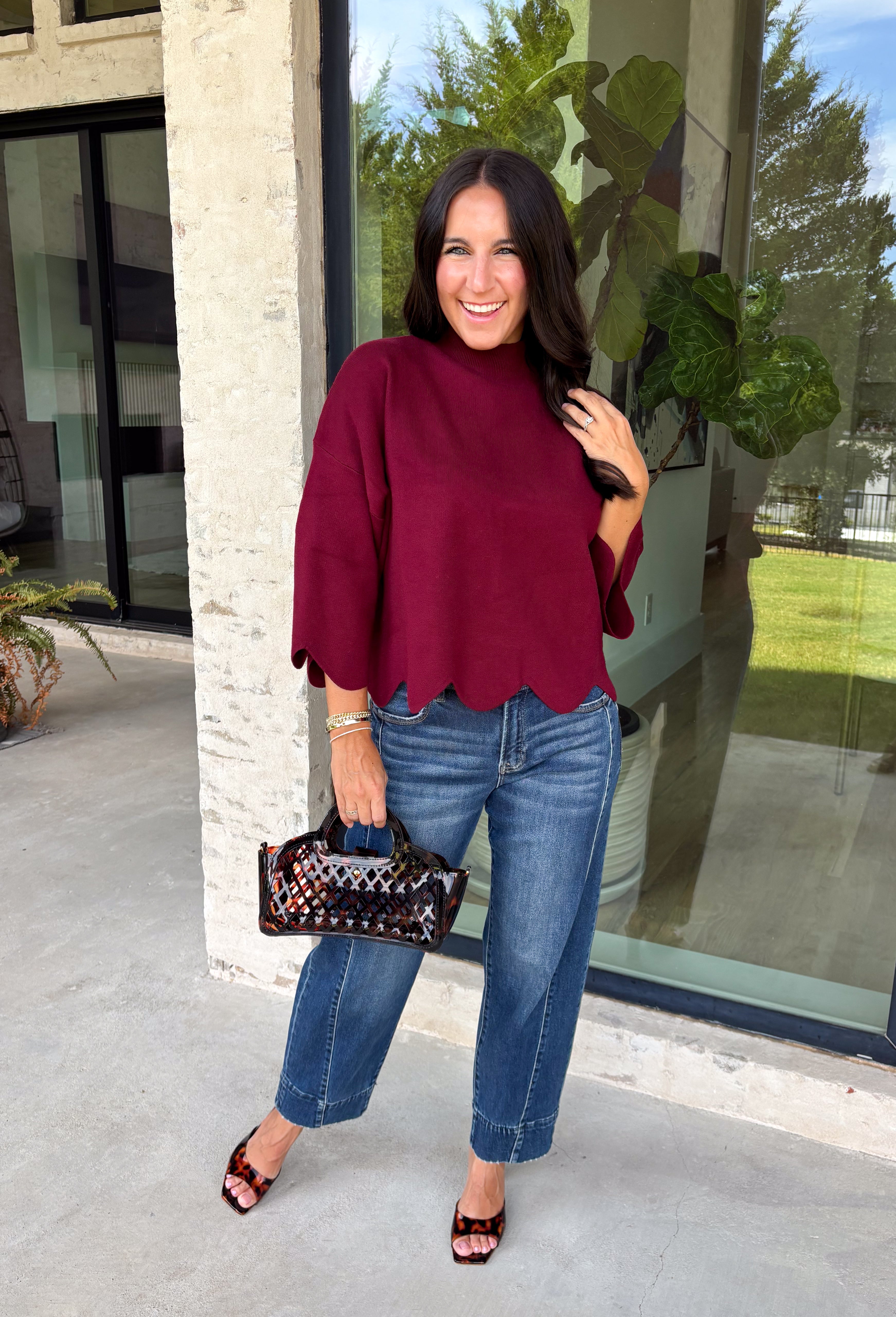 Rich merlot color makes this sweater top from Entro an instant favorite for the cooler months. The deep wine-inspired shade adds the perfect pop of seasonal color while still pairing easily with denim, cream, camel, and other autumn neutrals. A mock neckline gives it a classic look, while scalloped edges along the hem and sleeves add a sweet, unexpected finish. The ¾ length sleeves make it an easy transitional piece for warmer fall afternoons and chilly days ahead. 