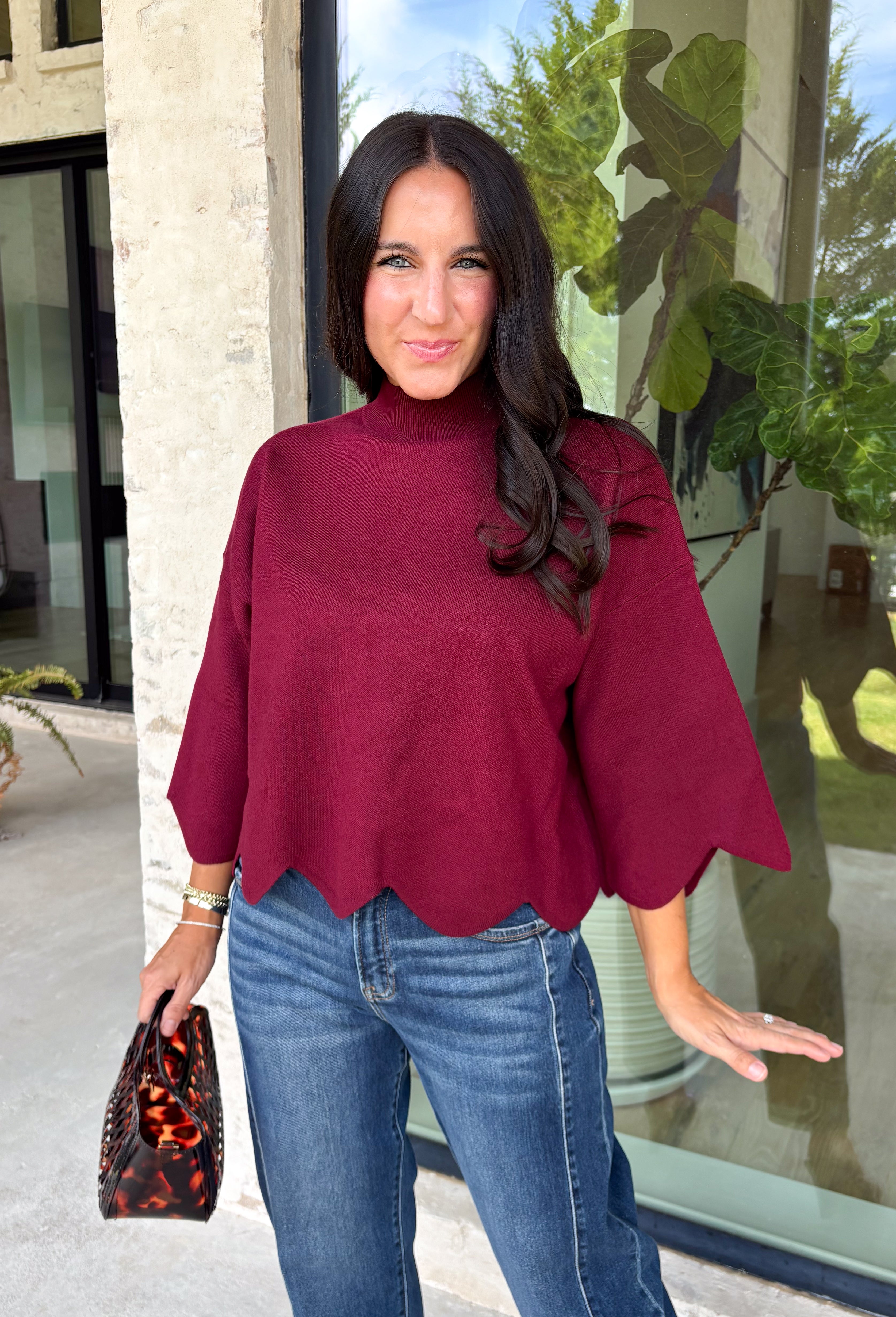 Rich merlot color makes this sweater top from Entro an instant favorite for the cooler months. The deep wine-inspired shade adds the perfect pop of seasonal color while still pairing easily with denim, cream, camel, and other autumn neutrals. A mock neckline gives it a classic look, while scalloped edges along the hem and sleeves add a sweet, unexpected finish. The ¾ length sleeves make it an easy transitional piece for warmer fall afternoons and chilly days ahead. 