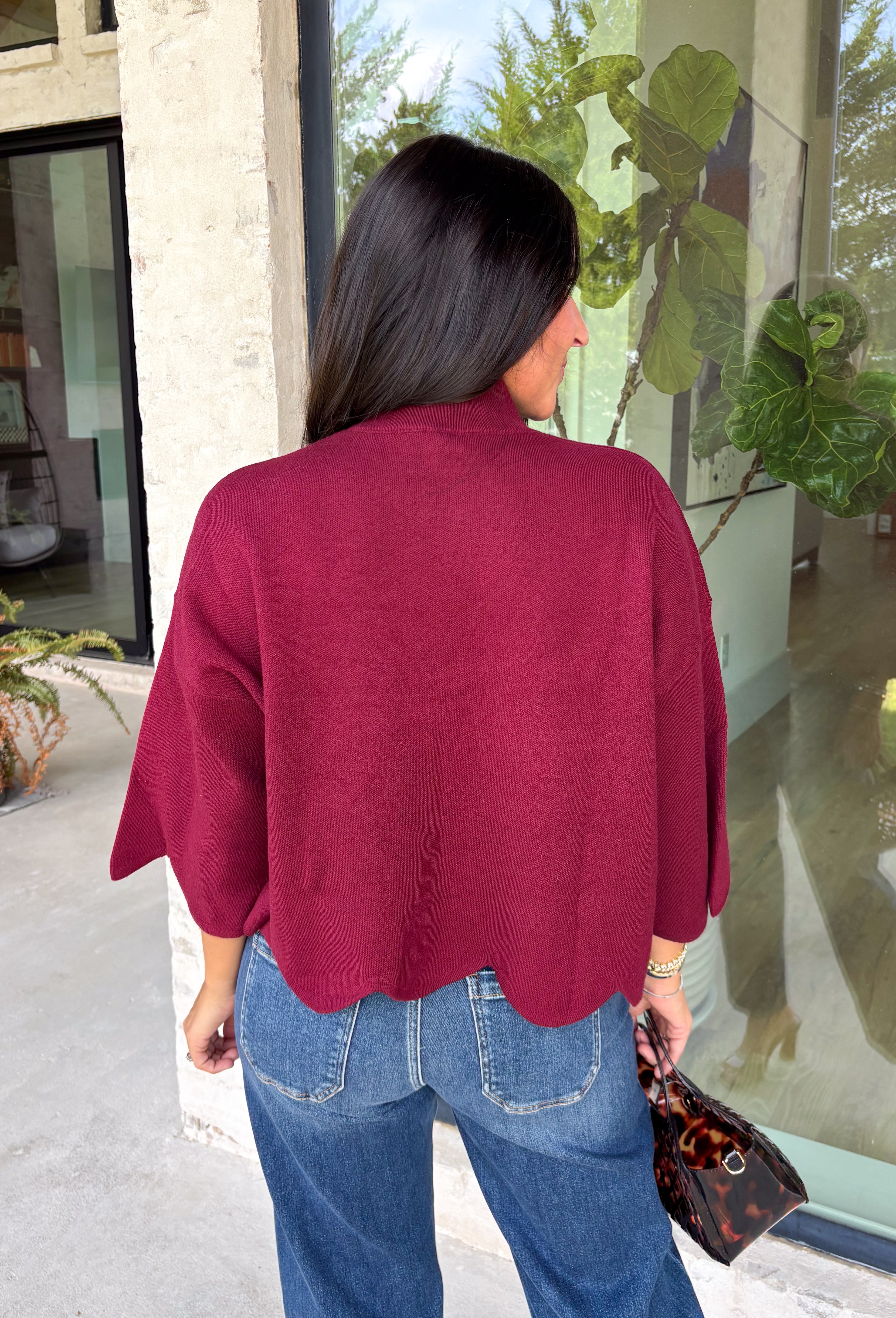 Rich merlot color makes this sweater top from Entro an instant favorite for the cooler months. The deep wine-inspired shade adds the perfect pop of seasonal color while still pairing easily with denim, cream, camel, and other autumn neutrals. A mock neckline gives it a classic look, while scalloped edges along the hem and sleeves add a sweet, unexpected finish. The ¾ length sleeves make it an easy transitional piece for warmer fall afternoons and chilly days ahead. 