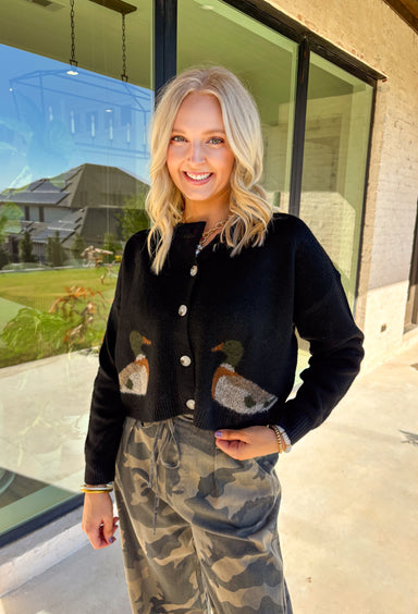 A cardigan with character—this black knit sweater is anything but ordinary. Designed with a button-down front, it’s accented with two charming ducks on the front that bring a whimsical, playful twist to your fall wardrobe. The soft knit blend offers warmth and comfort, while the relaxed fit makes it perfect for layering over everything from tees to dresses. A fun conversation starter that still feels cozy enough for everyday wear.