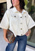 Meet the lightweight denim layer your wardrobe has been waiting for. This ecru short sleeve jacket from Entro gives classic denim a fresh update with a soft neutral shade and an easy draped silhouette. Snap buttons down the front keep the look casual, while chest pockets and additional front pockets add plenty of functional detail. Snap button closures at the sides give the design an unexpected finishing touch and add to its relaxed shape. 
