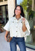 Meet the lightweight denim layer your wardrobe has been waiting for. This ecru short sleeve jacket from Entro gives classic denim a fresh update with a soft neutral shade and an easy draped silhouette. Snap buttons down the front keep the look casual, while chest pockets and additional front pockets add plenty of functional detail. Snap button closures at the sides give the design an unexpected finishing touch and add to its relaxed shape. 