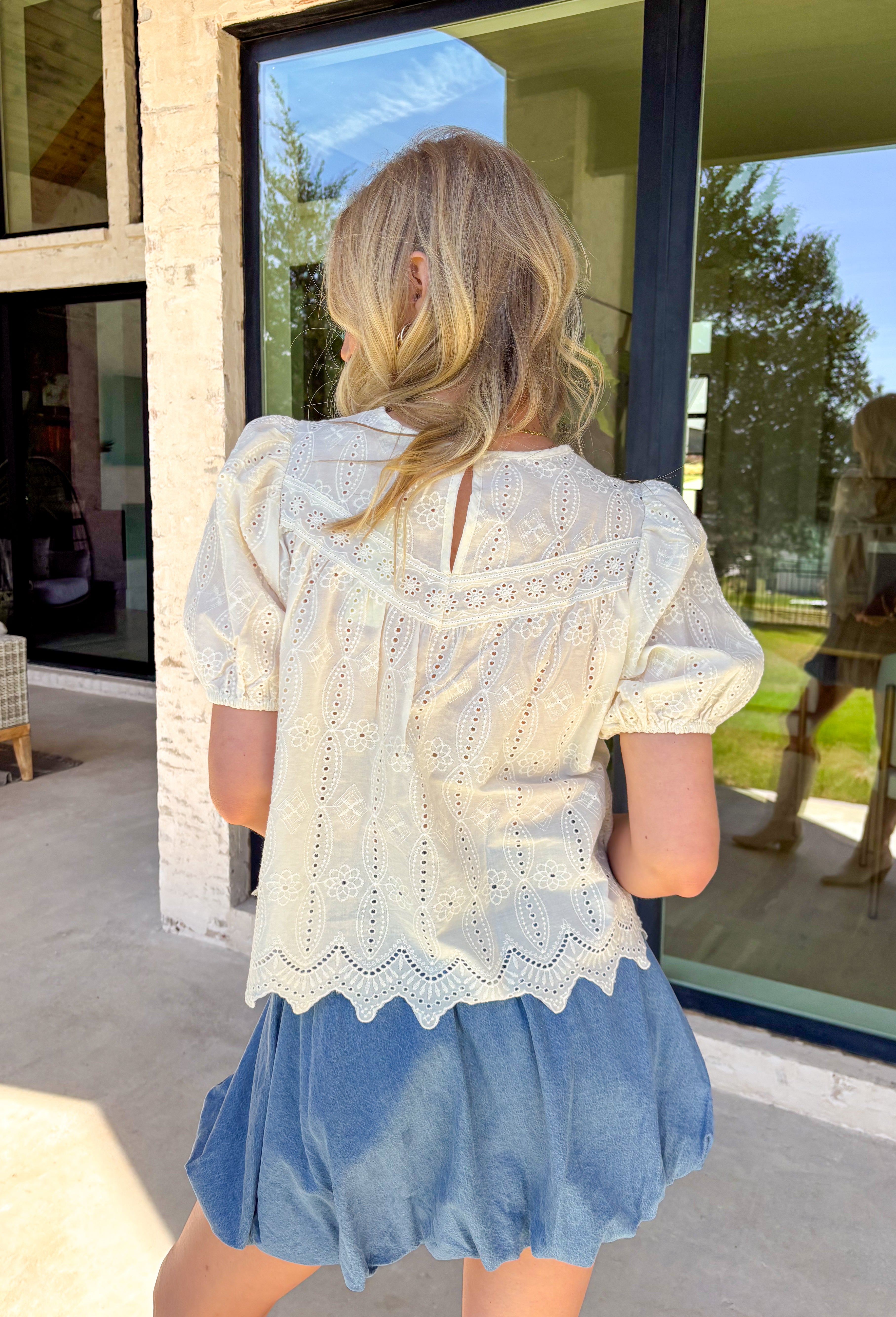 Sweet, airy, and made for sunny spring days, this ivory short sleeve top by Doe and Rae is the definition of effortless charm. Featuring eyelet lace throughout, it adds the prettiest texture while still feeling light and breathable. Elastic sleeve openings give it a soft, comfy fit, and the scalloped hem adds a delicate finishing touch. Complete with a keyhole closure in the back, this top is perfect for dressing up denim, pairing with skirts, or styling for spring events.