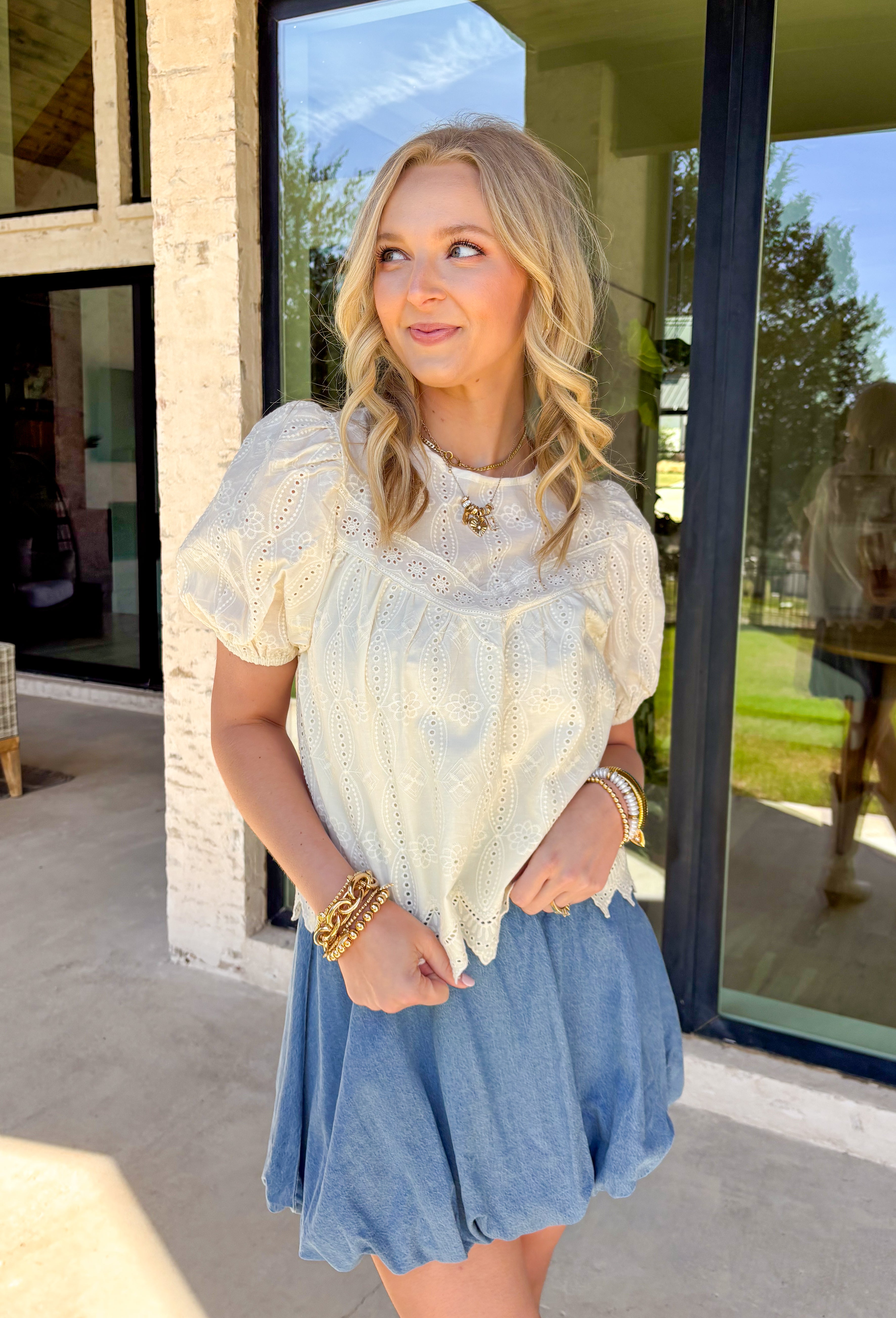 Sweet, airy, and made for sunny spring days, this ivory short sleeve top by Doe and Rae is the definition of effortless charm. Featuring eyelet lace throughout, it adds the prettiest texture while still feeling light and breathable. Elastic sleeve openings give it a soft, comfy fit, and the scalloped hem adds a delicate finishing touch. Complete with a keyhole closure in the back, this top is perfect for dressing up denim, pairing with skirts, or styling for spring events.