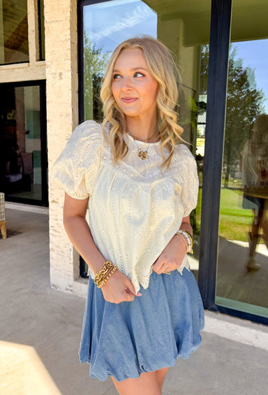 Sweet, airy, and made for sunny spring days, this ivory short sleeve top by Doe and Rae is the definition of effortless charm. Featuring eyelet lace throughout, it adds the prettiest texture while still feeling light and breathable. Elastic sleeve openings give it a soft, comfy fit, and the scalloped hem adds a delicate finishing touch. Complete with a keyhole closure in the back, this top is perfect for dressing up denim, pairing with skirts, or styling for spring events.