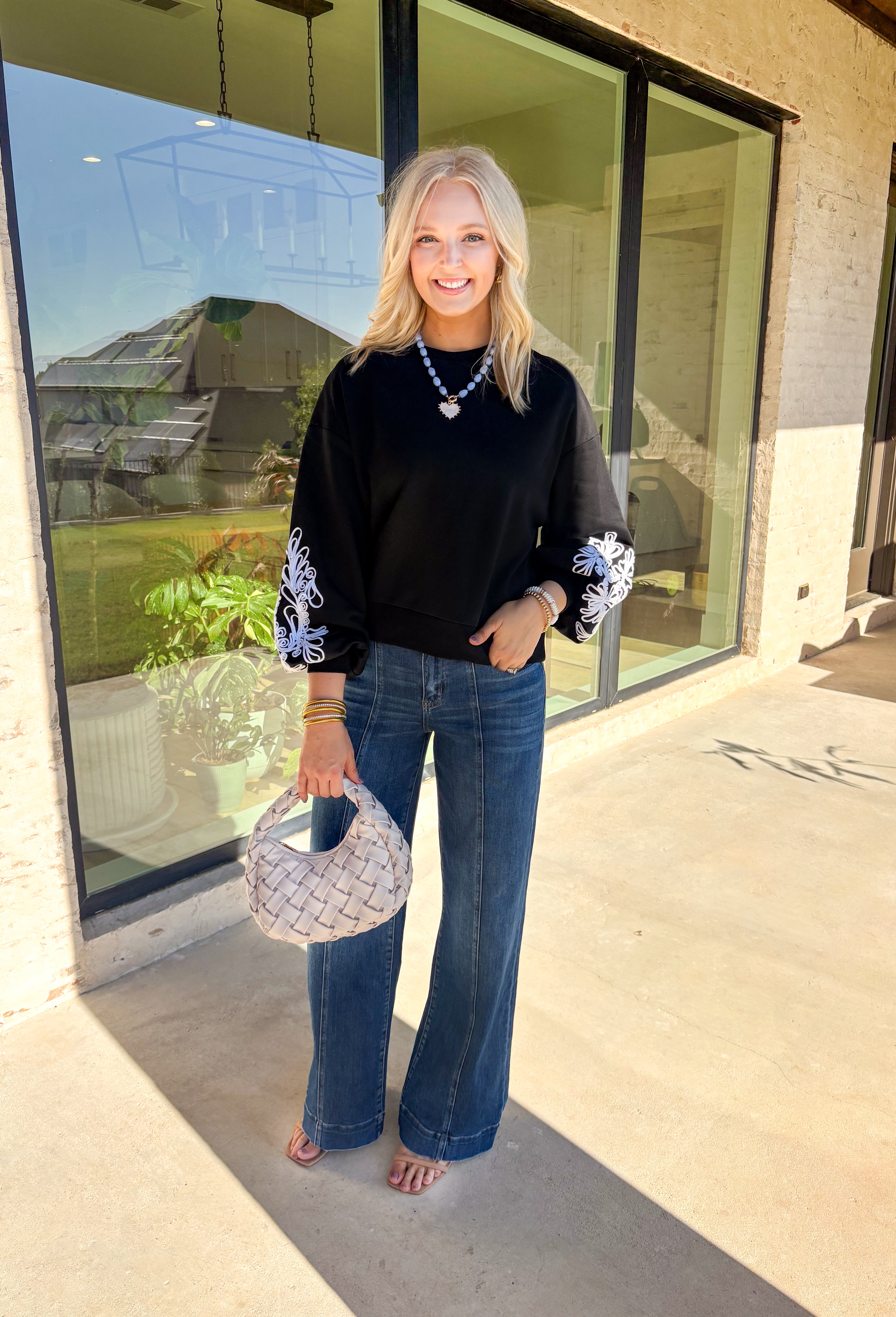 Standout sleeves make this black pullover a fall favorite. Designed with bold white embroidery, the pattern brings striking contrast and texture, while the ribbed cuffs create a softly billowed effect at the wrists. A ribbed hem completes the look, giving the sweater a polished yet cozy finish. Made from a soft cotton-blend knit, it’s perfect for layering into your everyday wardrobe while keeping that touch of bold, artistic flair.