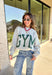 Two moods, one cozy pullover. This reversible mock neck sweater gives you options with light gray on one side and soft white fleece on the other. Printed in hunter green, one side reads “Gym” while the reverse says “Bed,” letting you wear your vibe for the day. With its oversized fit and cozy texture, it’s the perfect piece for lounging, layering, or heading out in casual comfort.