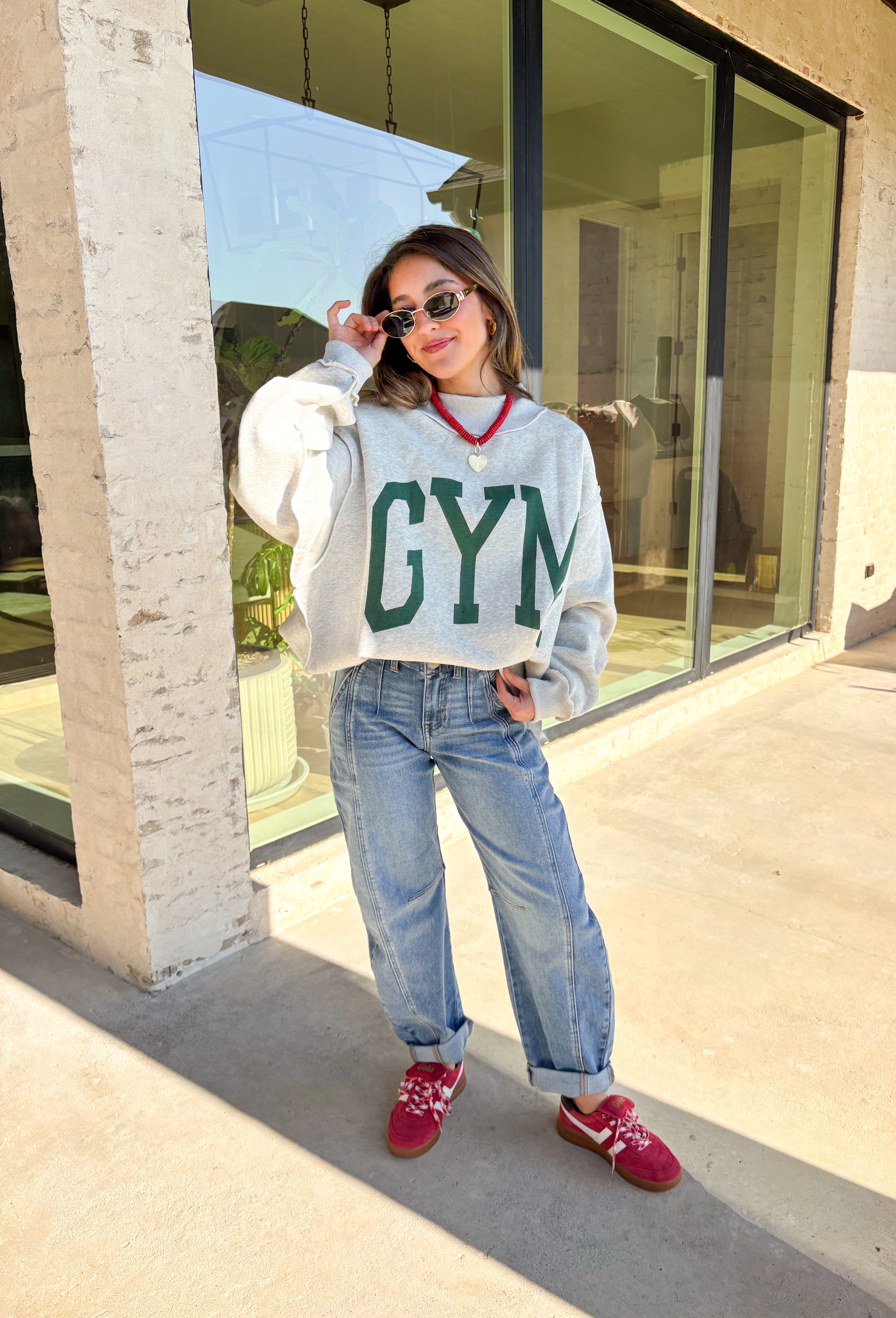 Two moods, one cozy pullover. This reversible mock neck sweater gives you options with light gray on one side and soft white fleece on the other. Printed in hunter green, one side reads “Gym” while the reverse says “Bed,” letting you wear your vibe for the day. With its oversized fit and cozy texture, it’s the perfect piece for lounging, layering, or heading out in casual comfort.