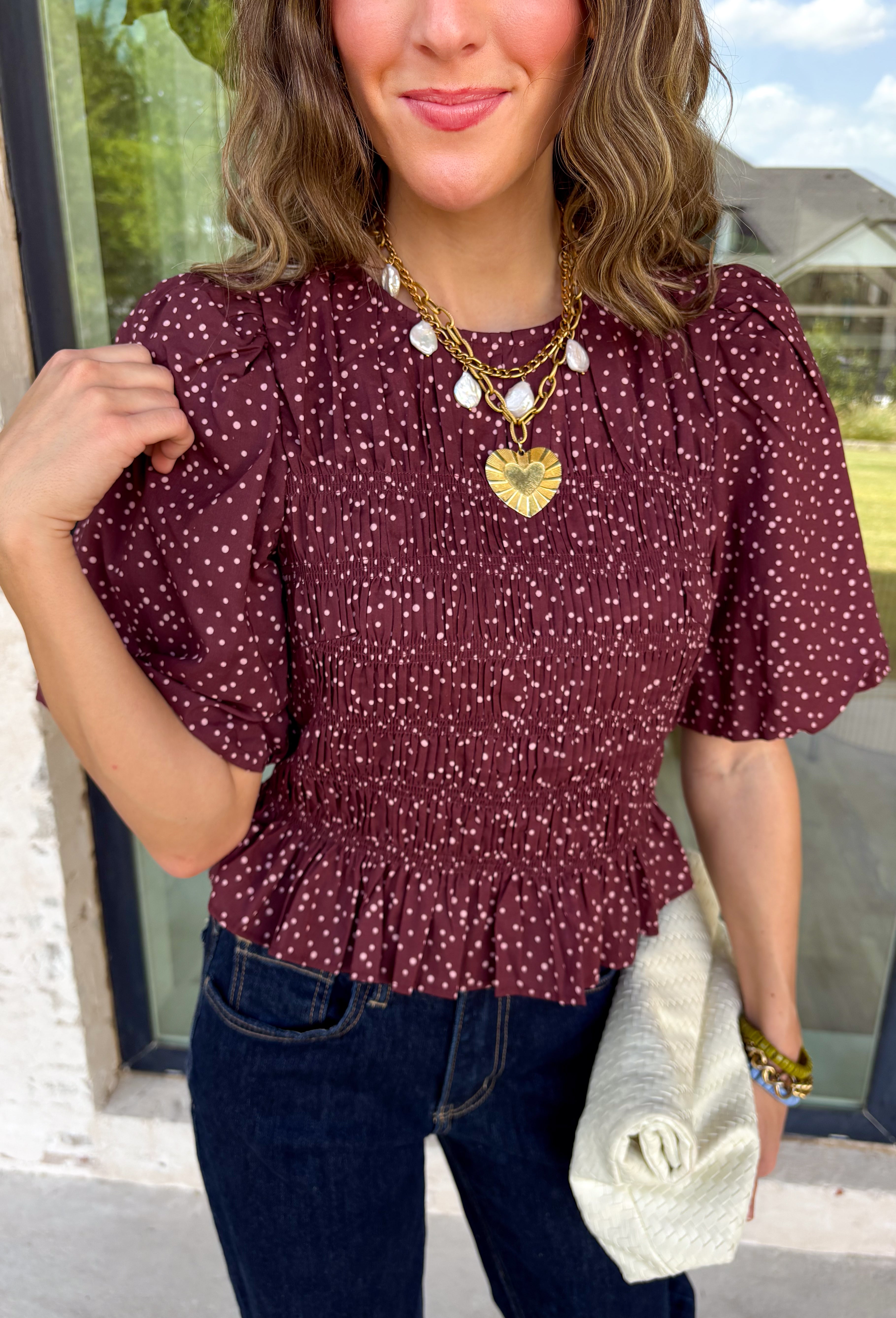 Add a playful touch to your fall wardrobe with this charming top from Entro. Designed in a rich plum hue with a light pink polka dot print, this feminine blouse is both timeless and fun. The smocked bodice creates a flattering, comfortable fit, while the puff sleeves add the perfect touch of romantic charm. Crafted from breathable cotton, this versatile top is easy to dress up for work or pair with denim for an effortless everyday look.