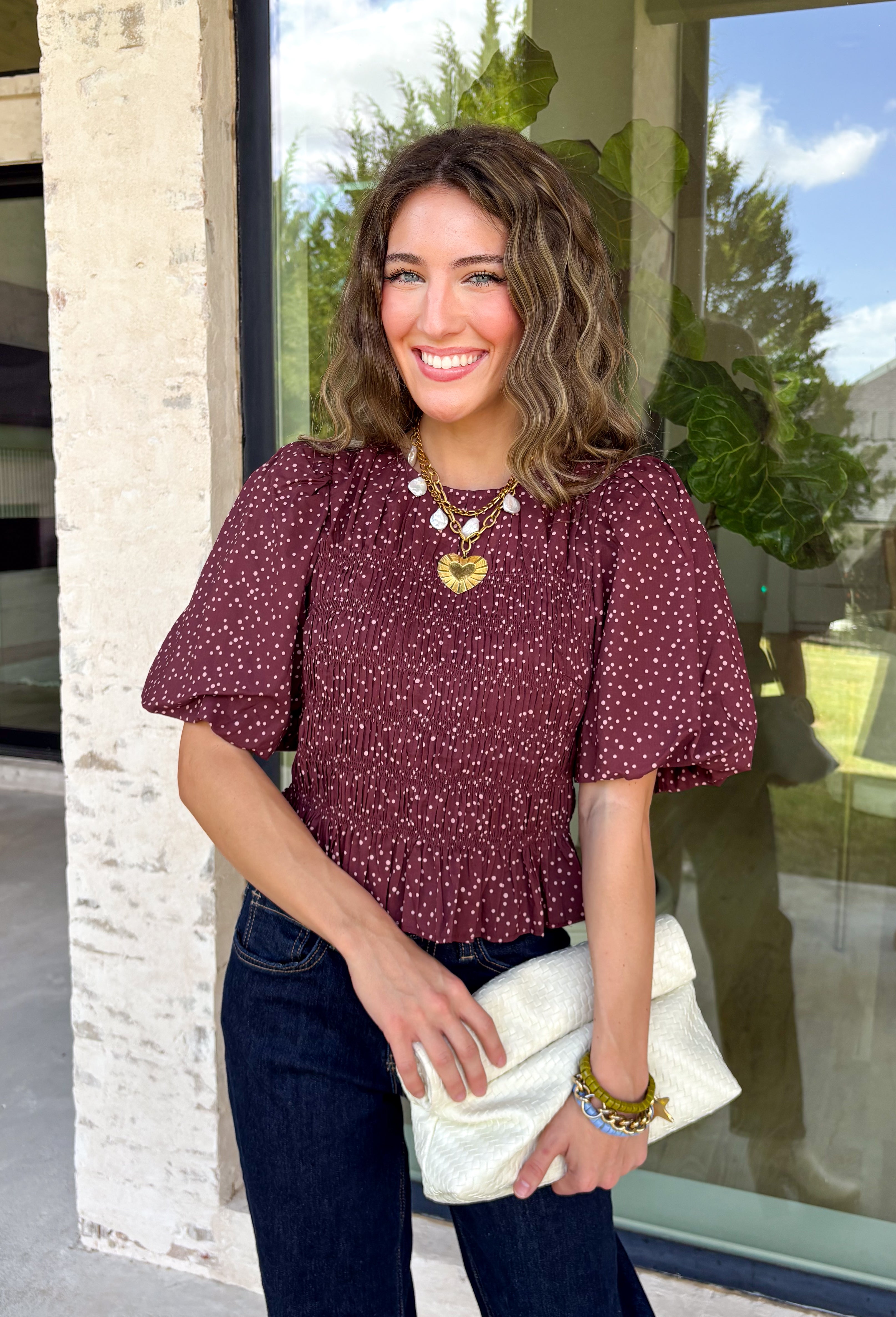 Add a playful touch to your fall wardrobe with this charming top from Entro. Designed in a rich plum hue with a light pink polka dot print, this feminine blouse is both timeless and fun. The smocked bodice creates a flattering, comfortable fit, while the puff sleeves add the perfect touch of romantic charm. Crafted from breathable cotton, this versatile top is easy to dress up for work or pair with denim for an effortless everyday look.