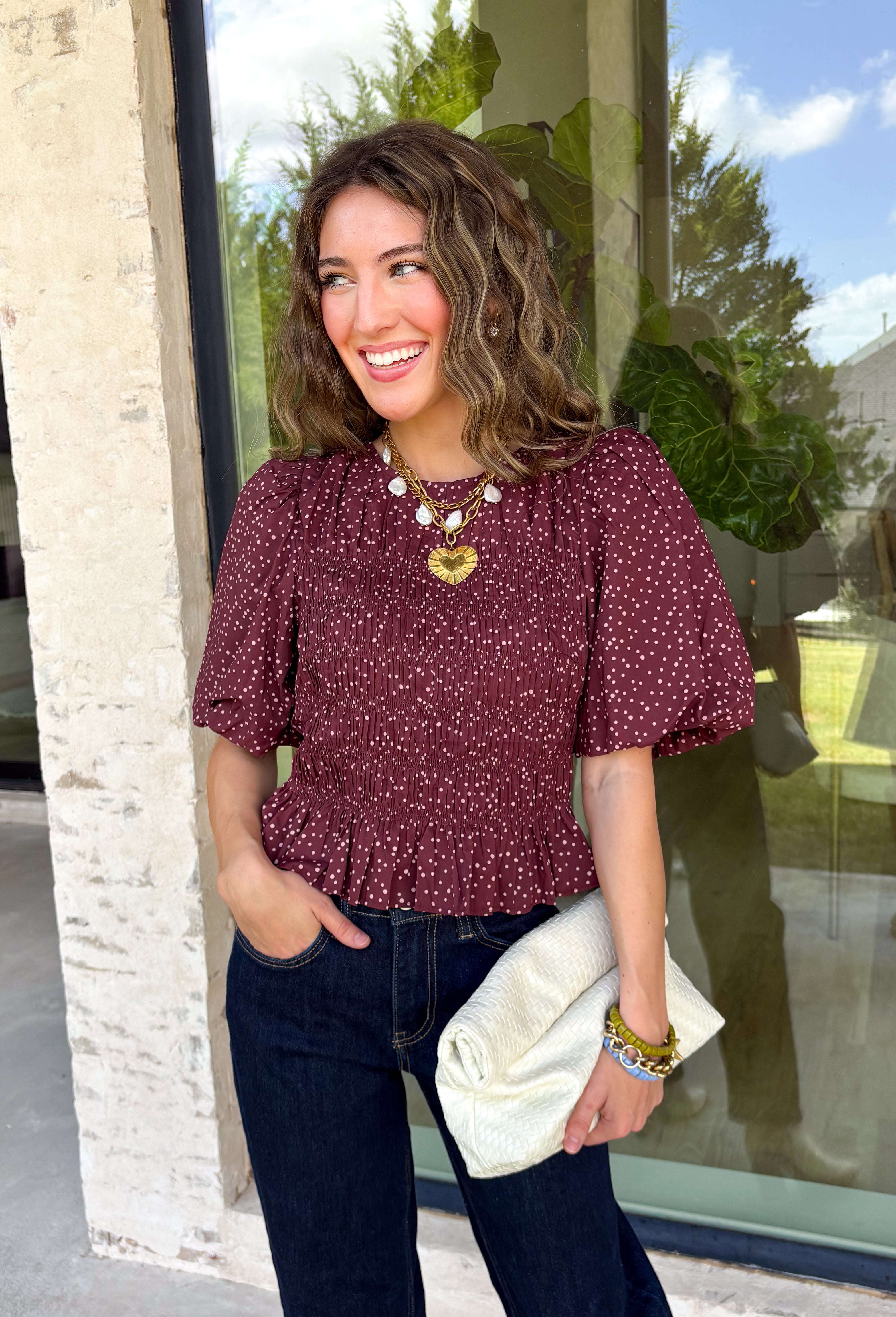 Add a playful touch to your fall wardrobe with this charming top from Entro. Designed in a rich plum hue with a light pink polka dot print, this feminine blouse is both timeless and fun. The smocked bodice creates a flattering, comfortable fit, while the puff sleeves add the perfect touch of romantic charm. Crafted from breathable cotton, this versatile top is easy to dress up for work or pair with denim for an effortless everyday look.