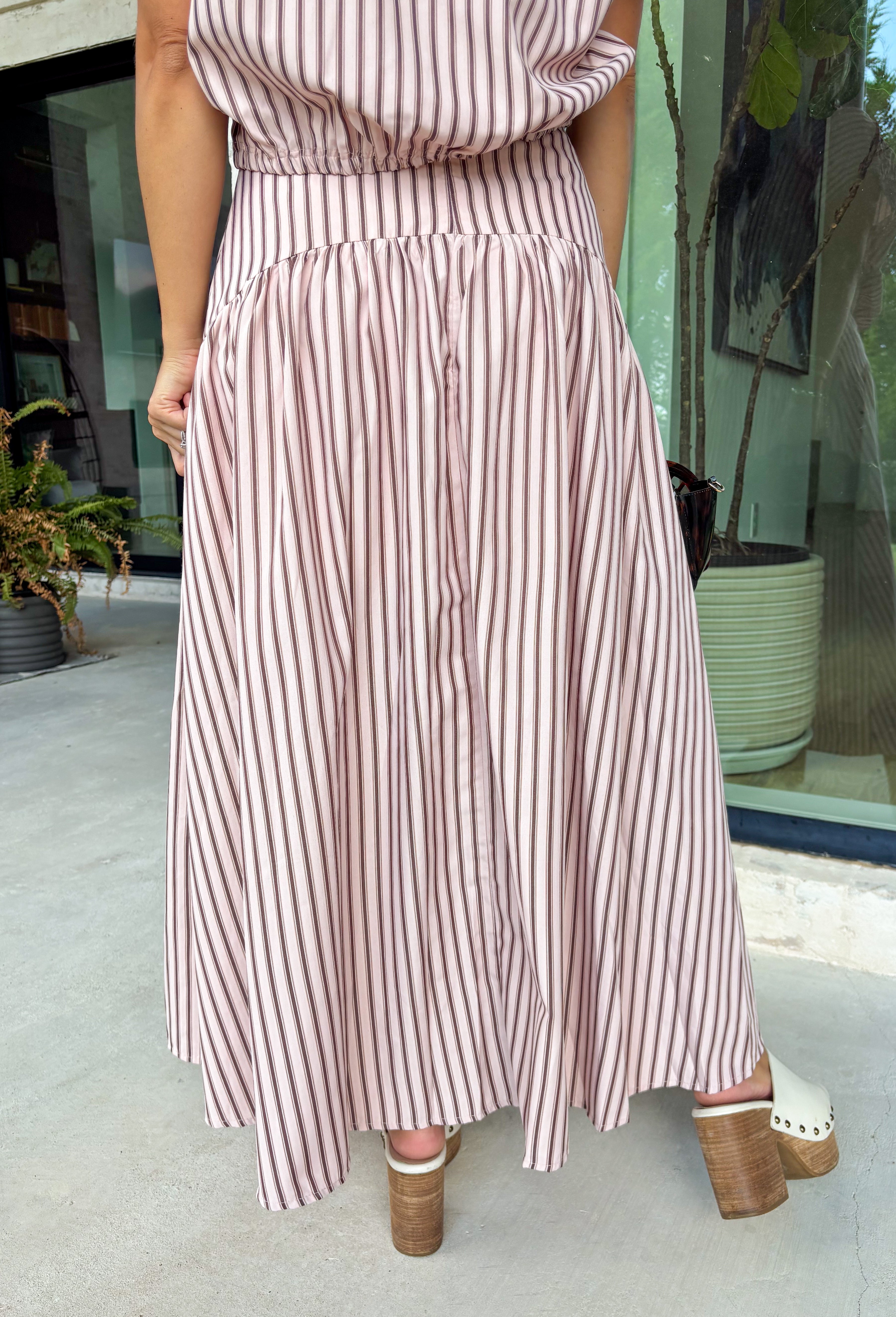 Soft pink meets warm brown in this charming midi skirt from Day + Moon. Featuring a classic stripe print, this feminine skirt brings a fresh pop of color to your fall wardrobe while still feeling easy and versatile. A zipper closure creates a clean, polished finish, while the midi length makes it perfect for everything from workdays and brunch dates to seasonal gatherings.