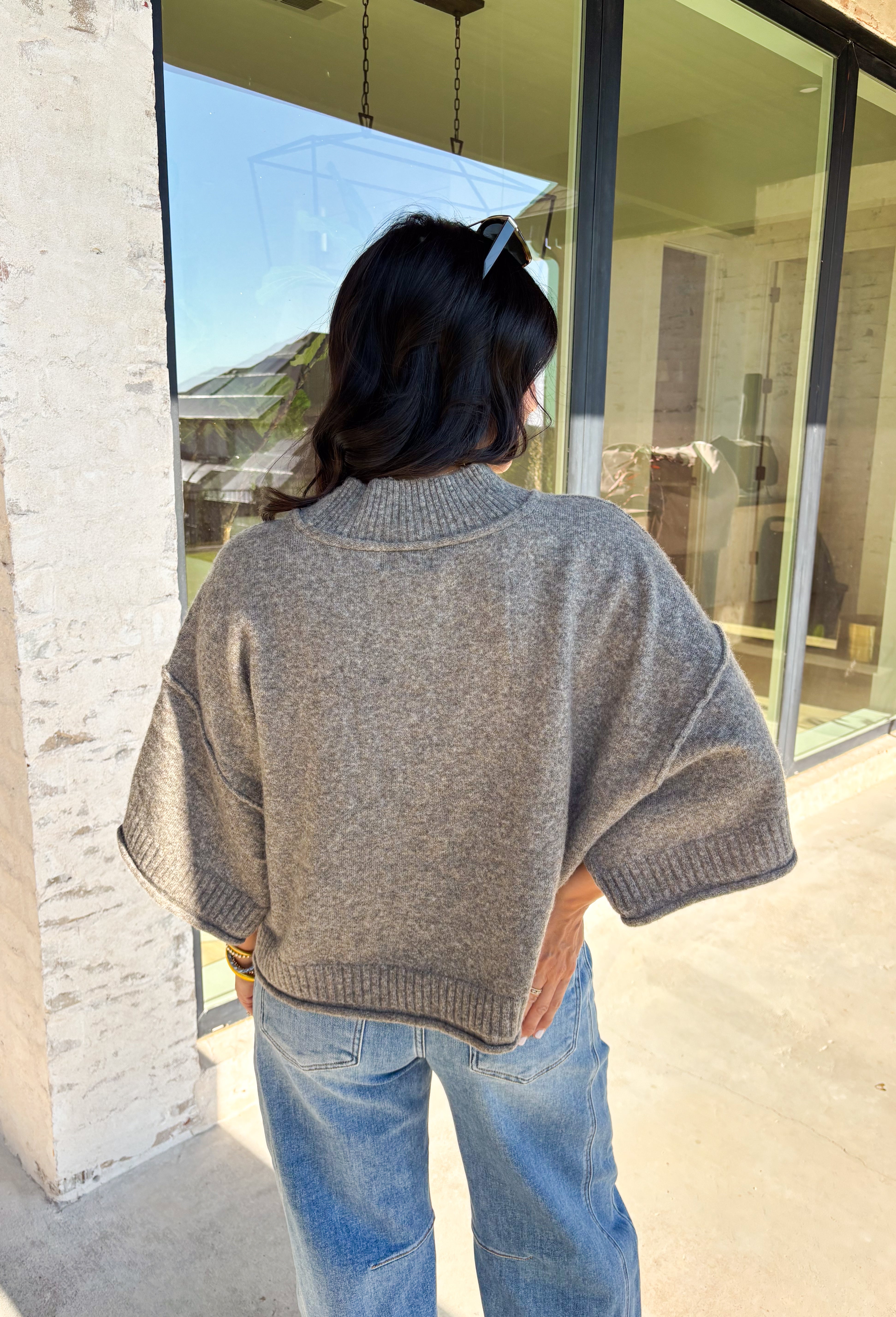 Cozy with a modern edge, this charcoal brown sweater is an easy go-to for cooler days. Designed with a mock neck and cropped length, it’s finished with exposed seam details that add a casual, laid-back vibe. Ribbed cuffs and hem bring structure to the soft knit, while the lightweight blend makes it perfect for layering. A versatile piece that pairs effortlessly with denim, skirts, or wide-leg pants for fall.