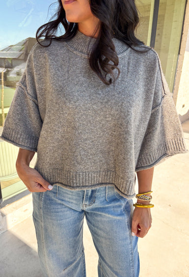 Cozy with a modern edge, this charcoal brown sweater is an easy go-to for cooler days. Designed with a mock neck and cropped length, it’s finished with exposed seam details that add a casual, laid-back vibe. Ribbed cuffs and hem bring structure to the soft knit, while the lightweight blend makes it perfect for layering. A versatile piece that pairs effortlessly with denim, skirts, or wide-leg pants for fall.