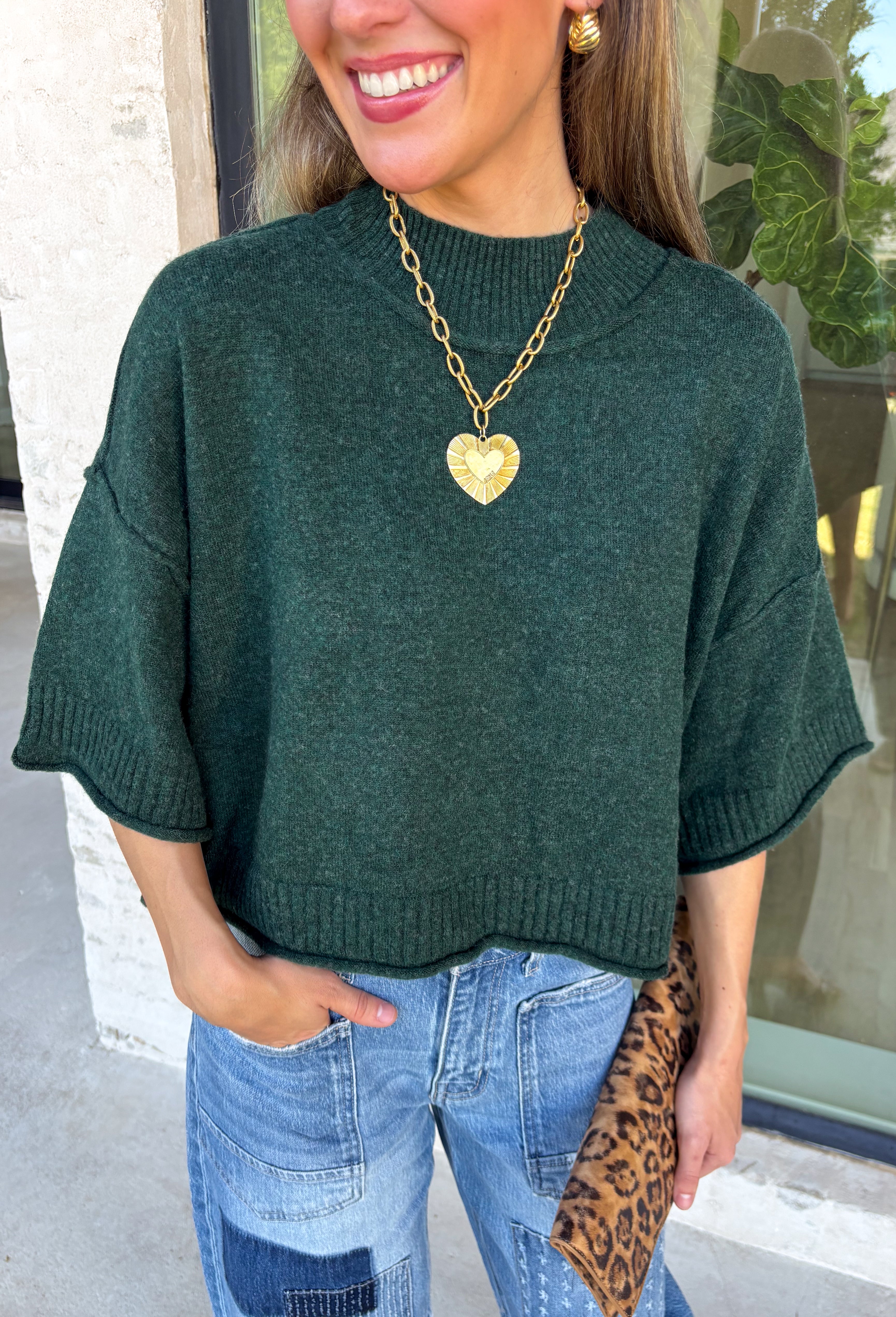 Cozy with a modern edge, this forest green sweater is an easy go-to for cooler days. Designed with a mock neck and cropped length, it’s finished with exposed seam details that add a casual, laid-back vibe. Ribbed cuffs and hem bring structure to the soft knit, while the lightweight blend makes it perfect for layering. A versatile piece that pairs effortlessly with denim, skirts, or wide-leg pants for fall.