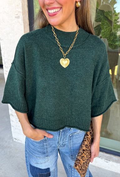 Cozy with a modern edge, this forest green sweater is an easy go-to for cooler days. Designed with a mock neck and cropped length, it’s finished with exposed seam details that add a casual, laid-back vibe. Ribbed cuffs and hem bring structure to the soft knit, while the lightweight blend makes it perfect for layering. A versatile piece that pairs effortlessly with denim, skirts, or wide-leg pants for fall.