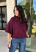 Rich wine color meets cozy knit texture in this short sleeve sweater from &amp; Merci. The deep seasonal shade makes it an easy way to add a little color to your cooler-weather wardrobe while still pairing beautifully with denim and neutral bottoms. A mock neckline gives it a classic finish, while exposed hems add a relaxed, lived-in touch. Ribbed detailing along the neckline, sleeve cuffs, and hem completes the look and adds extra texture throughout. 