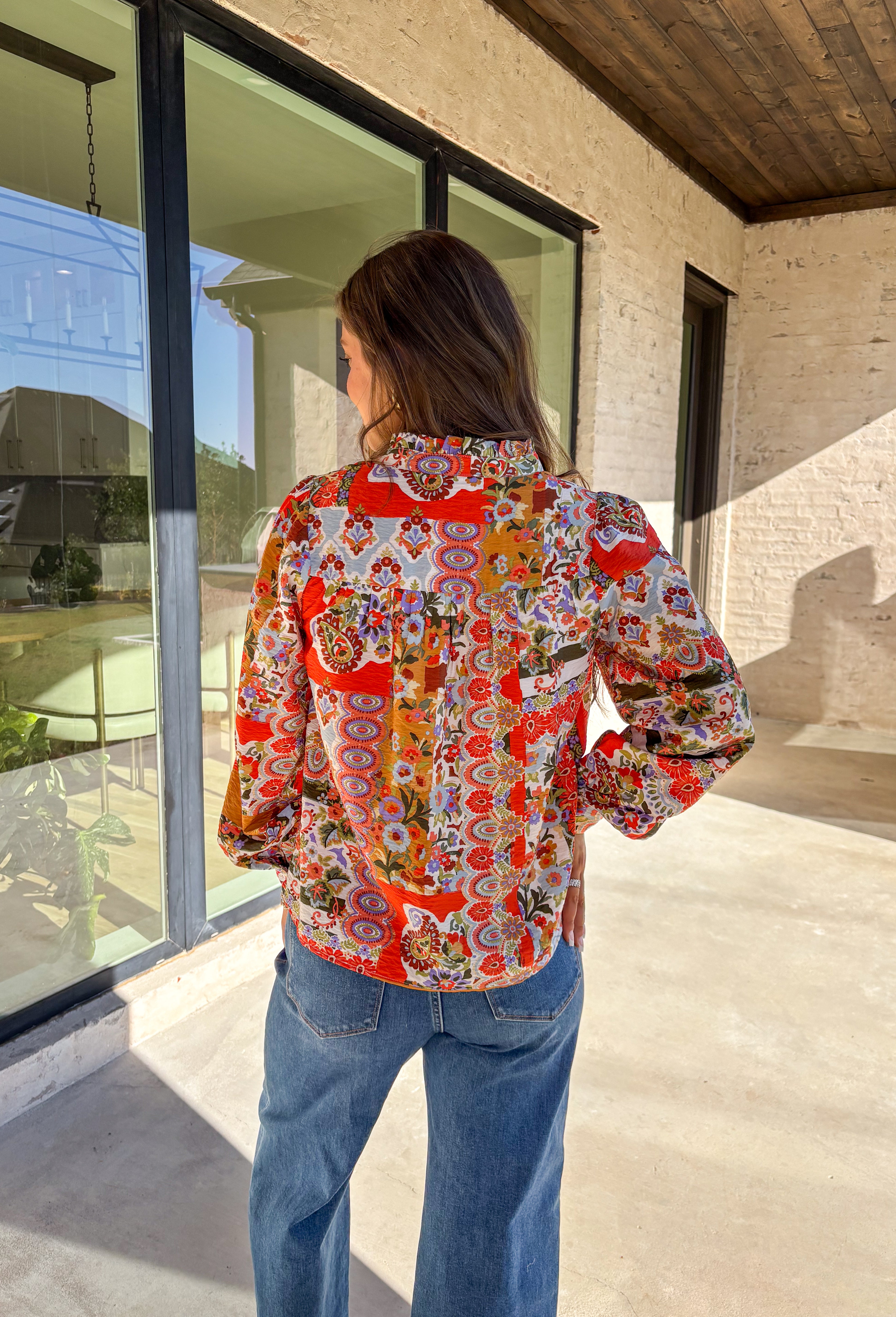 Bring bold color and cheerful energy to your fall wardrobe with this long sleeve floral top by Fate. The mix of orange, off white, tan, brown, purple, and blue creates a stunning statement print that feels both playful and timeless. Designed with a subtle ruffle neckline and a front tie detail, this blouse adds a soft feminine finish to your everyday look.