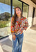 Bring bold color and cheerful energy to your fall wardrobe with this long sleeve floral top by Fate. The mix of orange, off white, tan, brown, purple, and blue creates a stunning statement print that feels both playful and timeless. Designed with a subtle ruffle neckline and a front tie detail, this blouse adds a soft feminine finish to your everyday look.