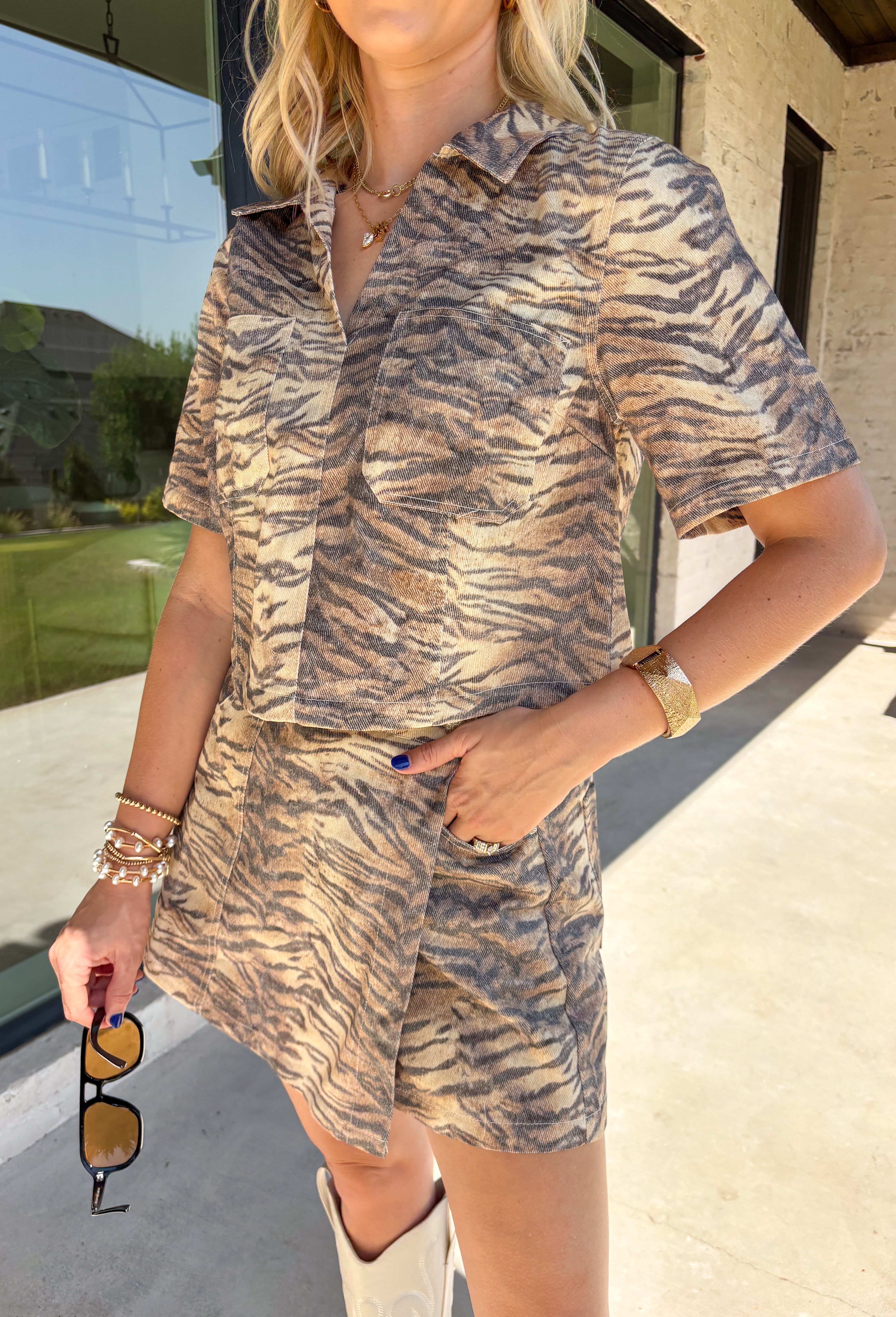 Take a walk on the wild side with this neutral zebra print top from Entro. Made from 100% cotton denim, it gives the classic animal print a fresh, structured feel that's perfect for transitioning into fall. The shirt collar keeps the look classic, while short sleeves and front patch pockets add a casual, laid-back touch. 