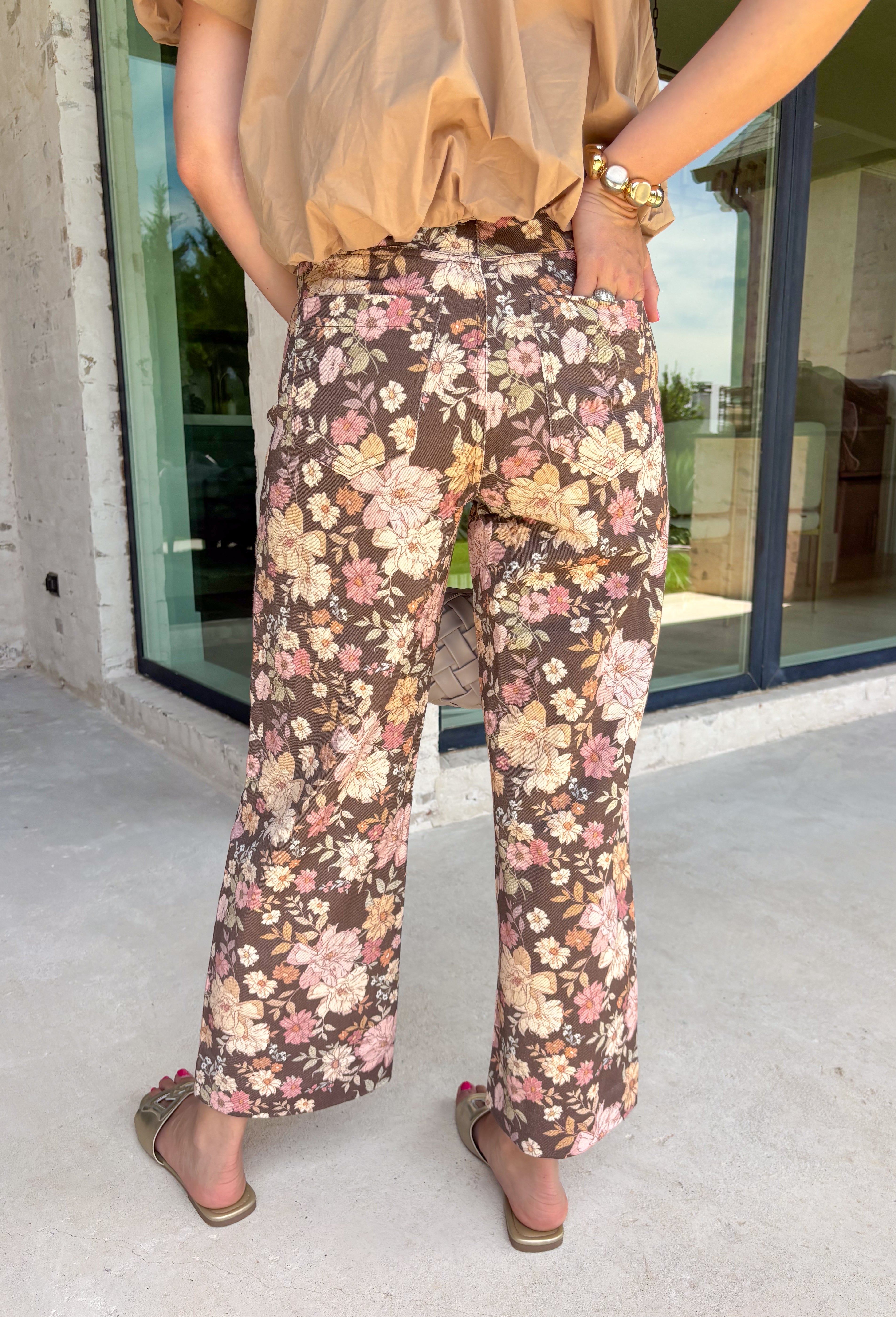 Give your fall wardrobe a fresh update with these beautifully printed floral pants. Featuring a rich brown backdrop with a bold neutral floral print, these statement pants are the perfect blend of timeless and trendy. Front seam detailing creates a flattering, elongated silhouette, while the classic zip-fly, button closure, and belt loops make them easy to style with all your favorite seasonal tops and sweaters. 