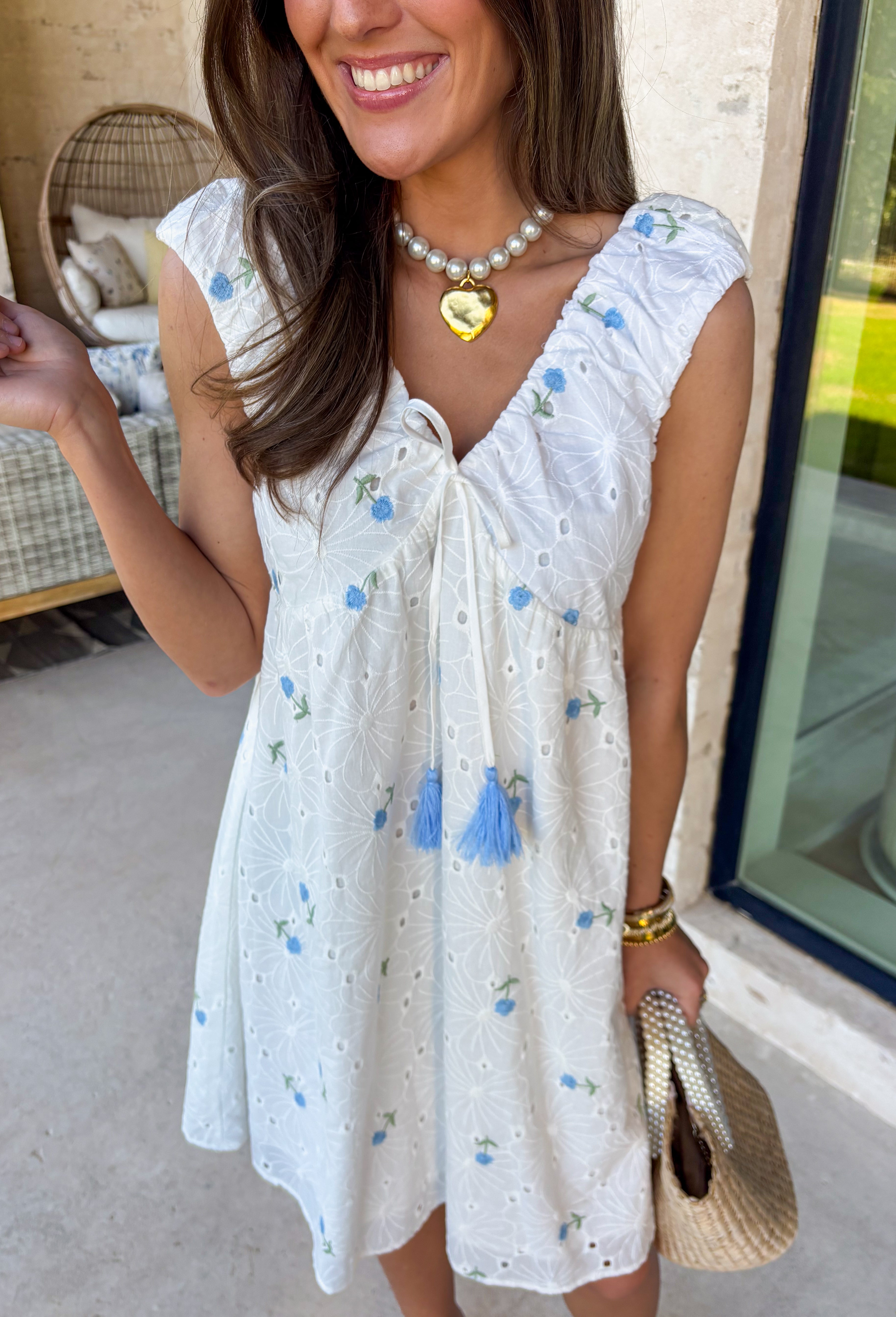 Light, airy, and made for sunny spring days, this white floral eyelet lace dress is as sweet as it gets. Dainty blue floral embroidery is scattered throughout, adding the prettiest pop of color against the crisp white backdrop. The eyelet lace texture gives it that timeless, feminine feel we all love this time of year. Designed with a flattering v-neckline and finished with a blue tassel tie detail, this dress blends charm and comfort effortlessly. 