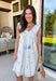 Light, airy, and made for sunny spring days, this white floral eyelet lace dress is as sweet as it gets. Dainty blue floral embroidery is scattered throughout, adding the prettiest pop of color against the crisp white backdrop. The eyelet lace texture gives it that timeless, feminine feel we all love this time of year. Designed with a flattering v-neckline and finished with a blue tassel tie detail, this dress blends charm and comfort effortlessly. 