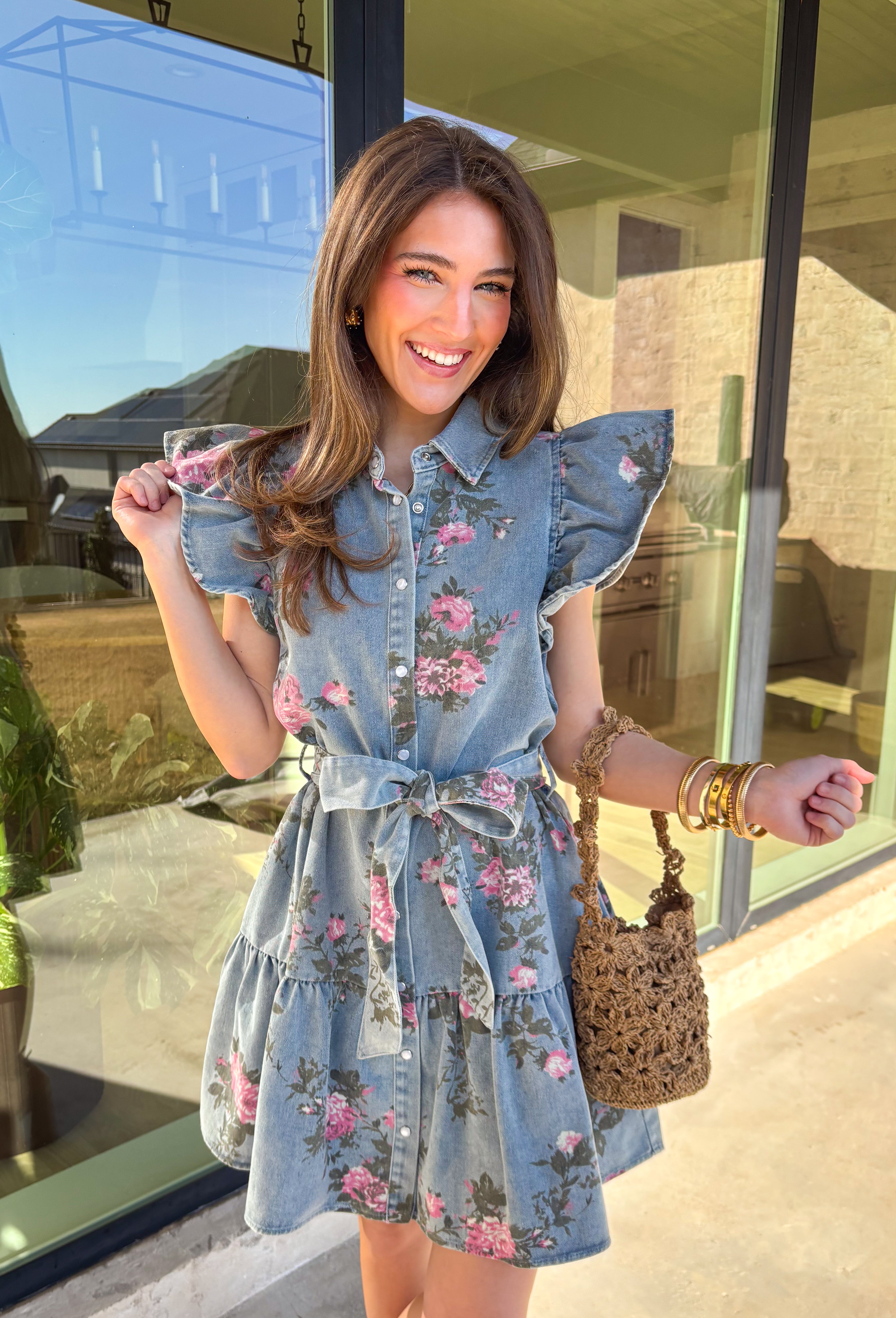 Denim, but make it spring! This short sleeve button-down denim dress by Entro is the cutest mix of classic and playful, featuring a pink floral print that instantly brightens up your look. The collared neckline and button-down front keep it polished, while the tiered skirt adds an easy, feminine flow. Finished with a matching self-tie belt to cinch the waist just right, this dress is perfect for brunch, spring events, or any day you want an effortless outfit that still feels special.