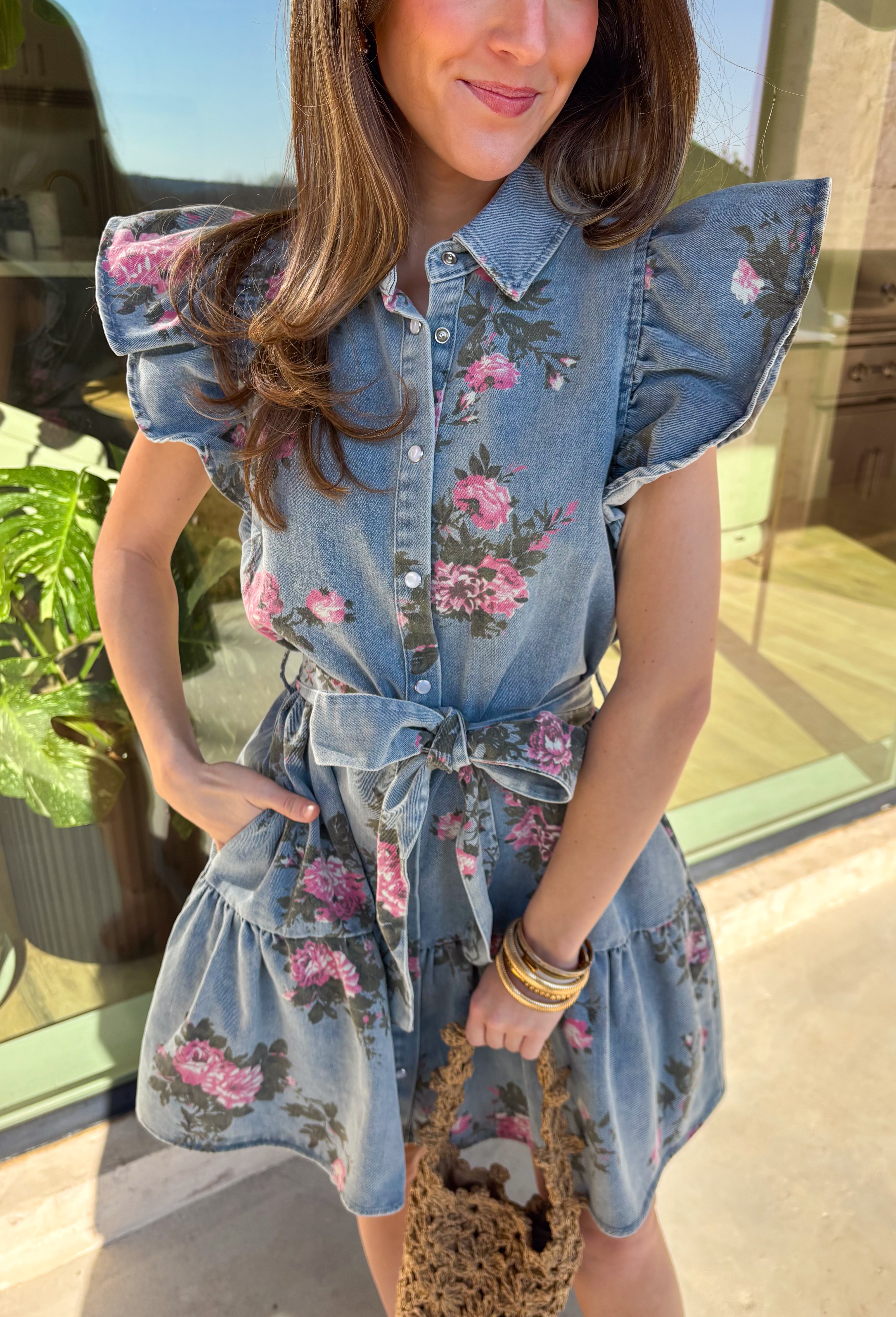 Denim, but make it spring! This short sleeve button-down denim dress by Entro is the cutest mix of classic and playful, featuring a pink floral print that instantly brightens up your look. The collared neckline and button-down front keep it polished, while the tiered skirt adds an easy, feminine flow. Finished with a matching self-tie belt to cinch the waist just right, this dress is perfect for brunch, spring events, or any day you want an effortless outfit that still feels special.