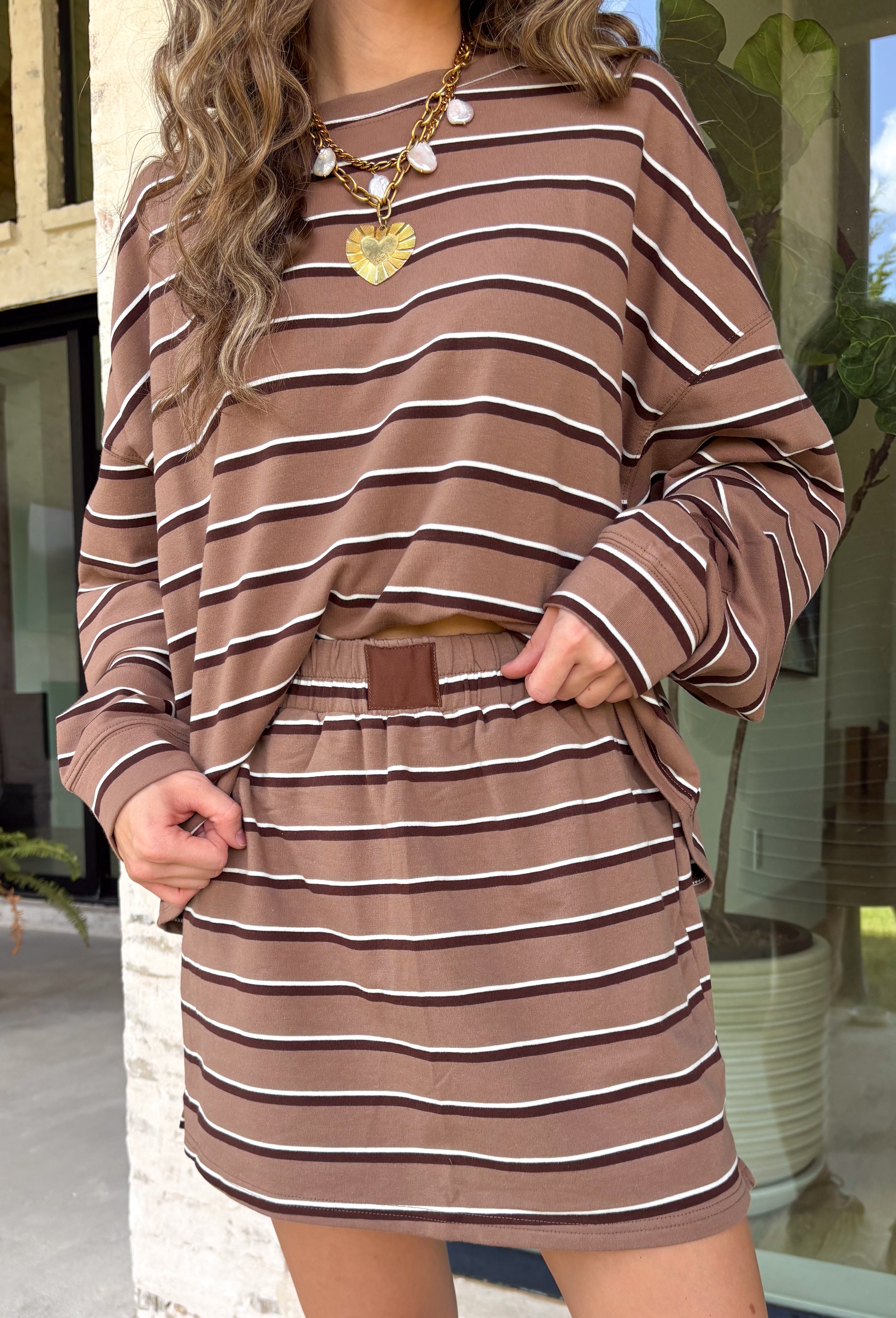 Bring warm, easy neutrals into your fall wardrobe with this striped skort from Day + Moon. Designed with a tan base and classic brown and ivory stripes, it has that effortless autumn color palette that pairs with just about everything. The elastic waistband keeps the fit comfortable, while the skort design gives you the look of a skirt with the ease and coverage of shorts. 