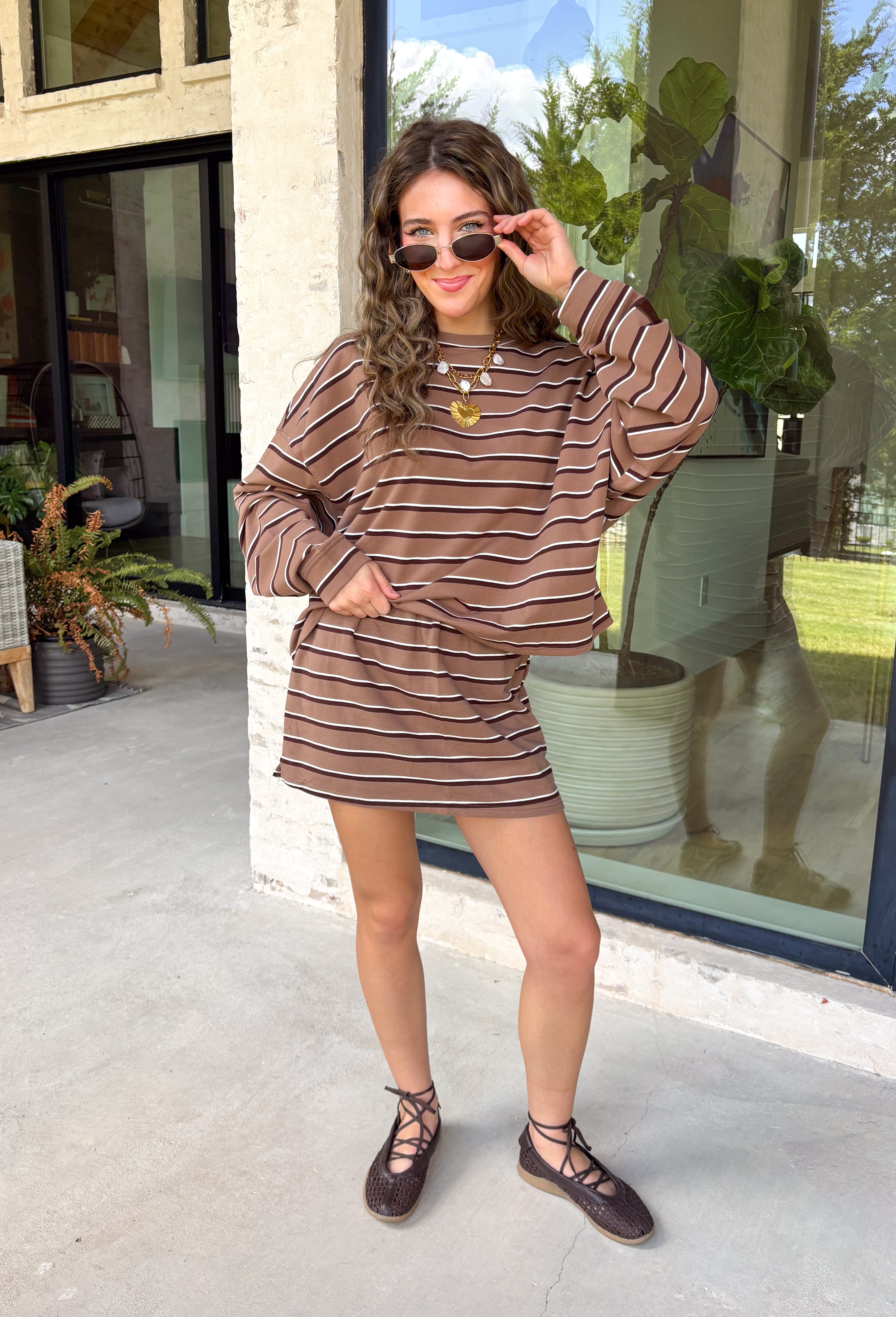 Neutral stripes make this long sleeve top from Day + Moon an easy favorite for the season. The tan base is paired with brown and ivory stripes for a warm color combination that fits right in with your fall wardrobe. Made from a soft cotton blend with a touch of stretch, it offers plenty of comfort for everything from workdays to weekend plans. 