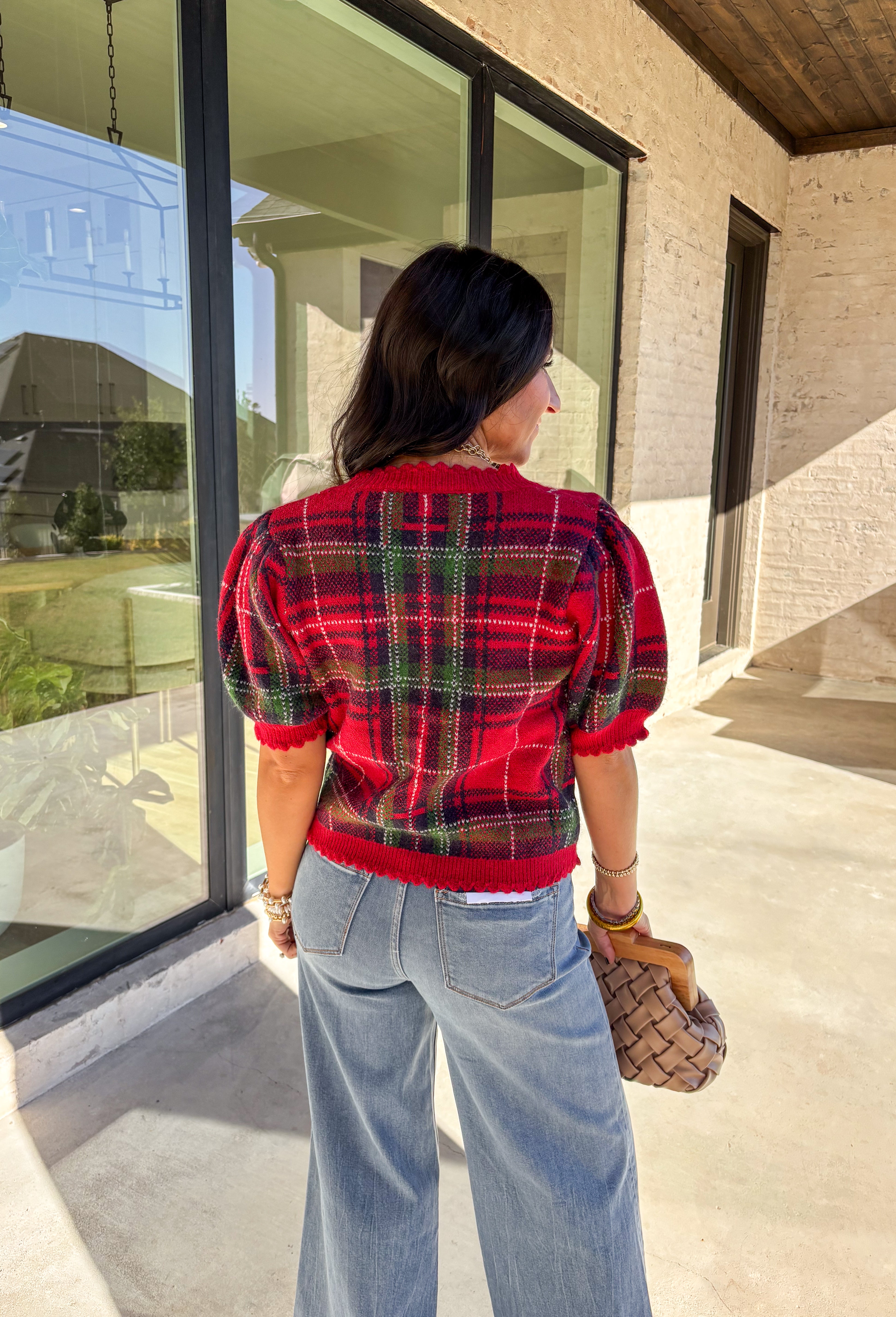Festive and cozy, this plaid sweater knit top is made to bring holiday cheer. Featuring short puff sleeves and a scallop edge neckline, it’s finished with a button-front closure for a cardigan-style fit. The bold red plaid pattern in holiday tones makes it a standout for seasonal gatherings, while the soft knit keeps it comfortable and easy to wear. Perfect for layering or styling on its own, this cardigan blends playful charm with cozy comfort.