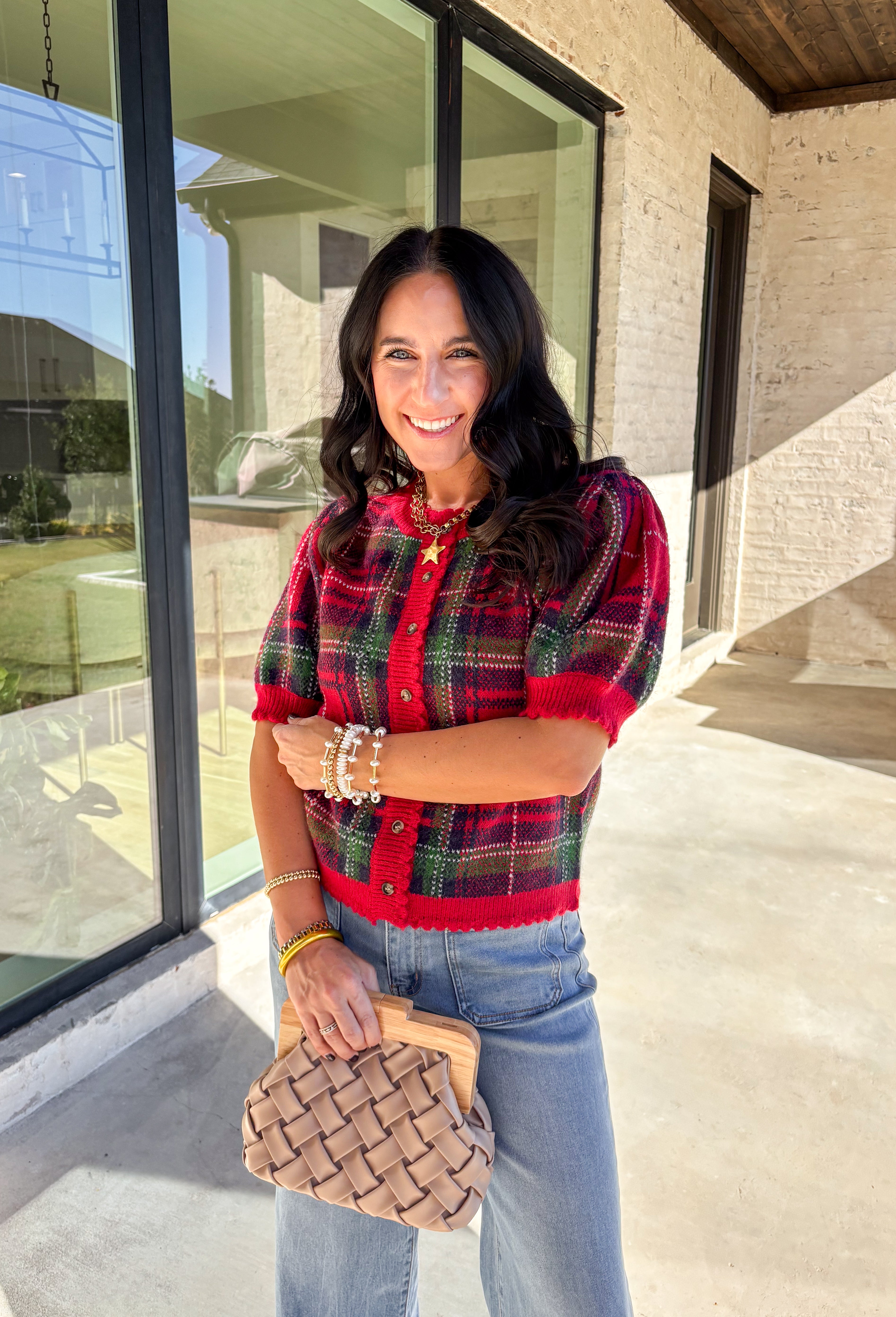 Festive and cozy, this plaid sweater knit top is made to bring holiday cheer. Featuring short puff sleeves and a scallop edge neckline, it’s finished with a button-front closure for a cardigan-style fit. The bold red plaid pattern in holiday tones makes it a standout for seasonal gatherings, while the soft knit keeps it comfortable and easy to wear. Perfect for layering or styling on its own, this cardigan blends playful charm with cozy comfort.