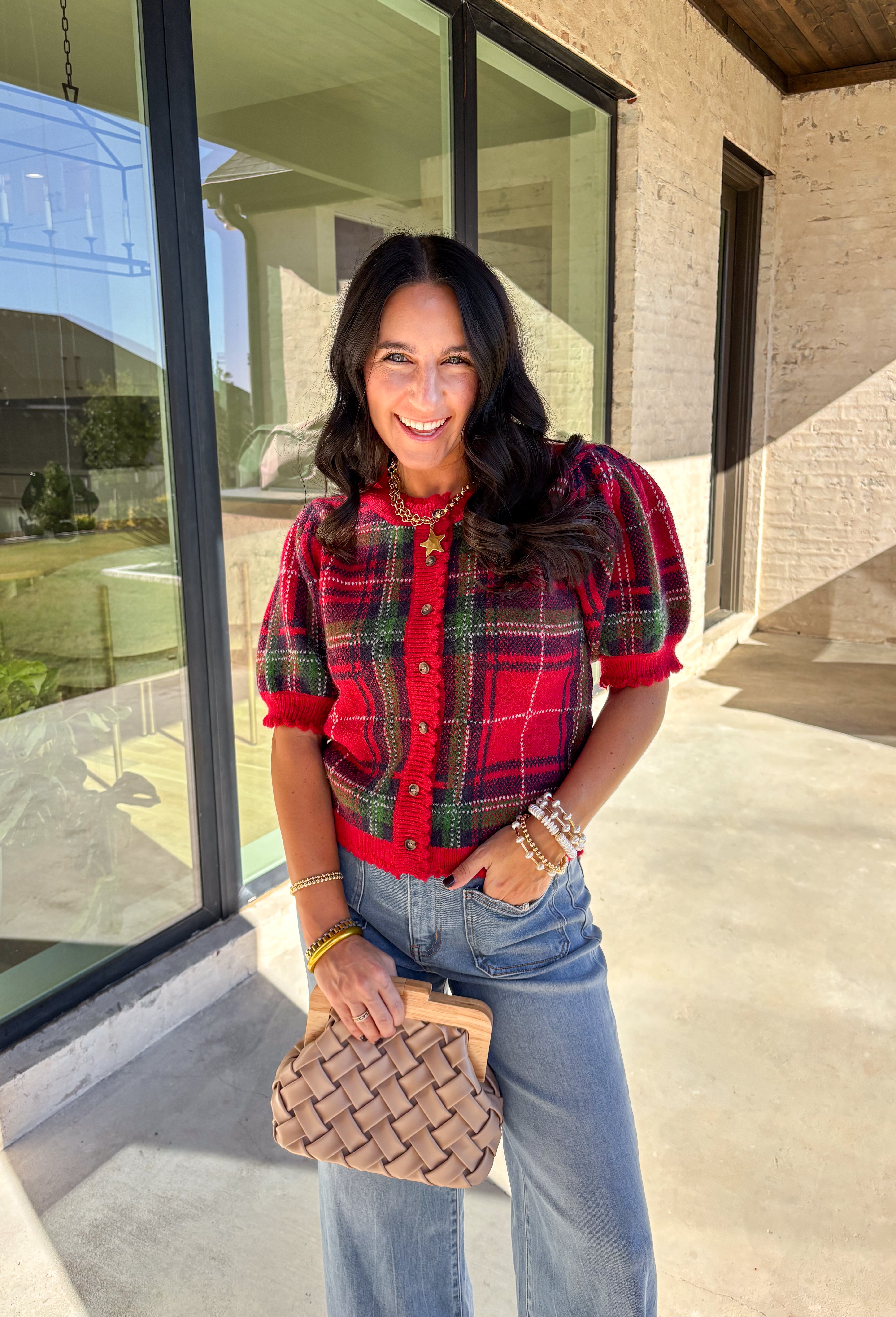 Festive and cozy, this plaid sweater knit top is made to bring holiday cheer. Featuring short puff sleeves and a scallop edge neckline, it’s finished with a button-front closure for a cardigan-style fit. The bold red plaid pattern in holiday tones makes it a standout for seasonal gatherings, while the soft knit keeps it comfortable and easy to wear. Perfect for layering or styling on its own, this cardigan blends playful charm with cozy comfort.