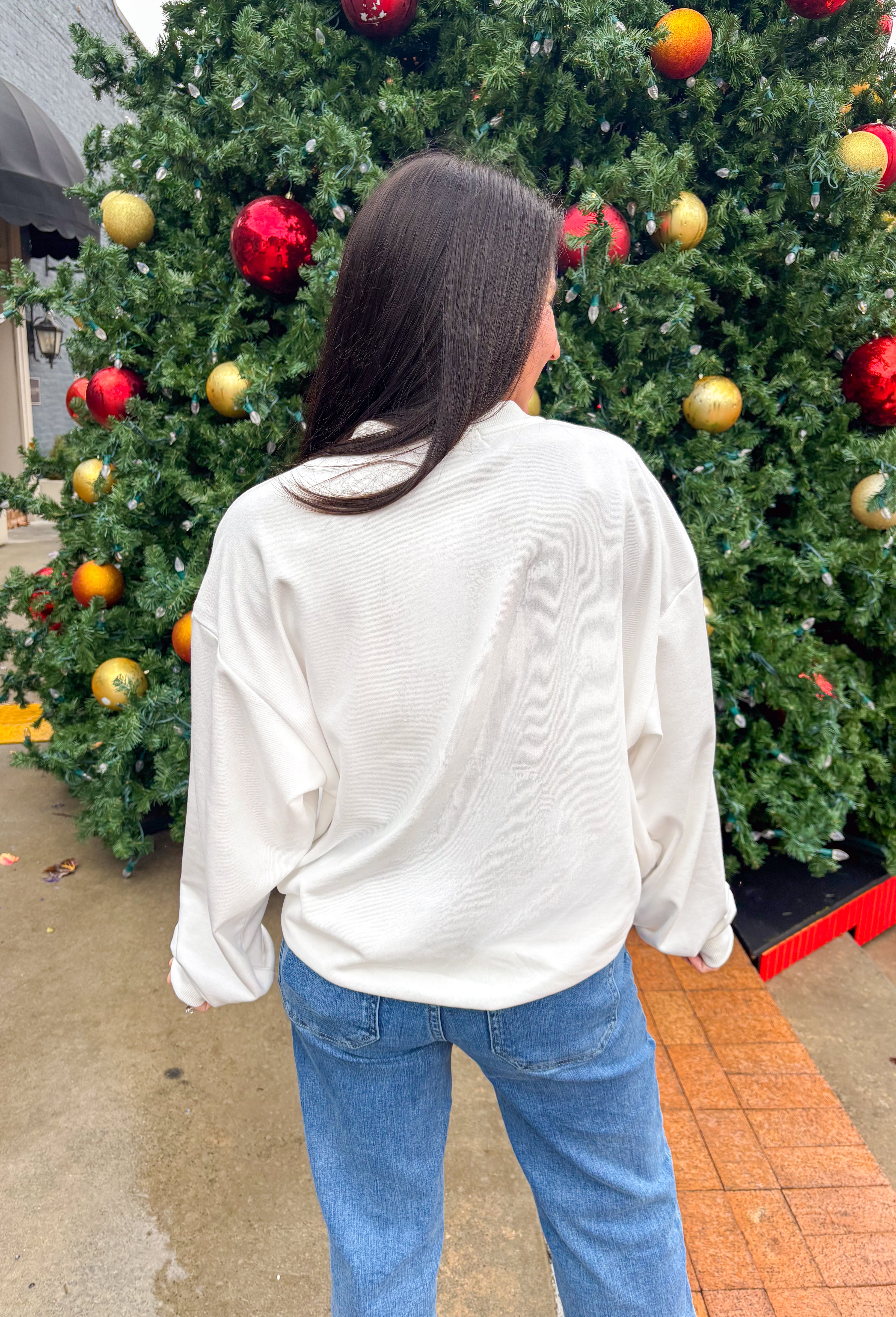 Stay merry and bright this season in the “Holly Jolly” pullover by Main Strip! This soft white lightweight sweatshirt features colorful gingham lettering—each letter a unique mix of festive color and pattern—outlined with white stitching for a playful holiday touch. Cozy and cheerful, it’s the perfect piece for decking the halls, sipping cocoa, or simply spreading a little Christmas joy.
