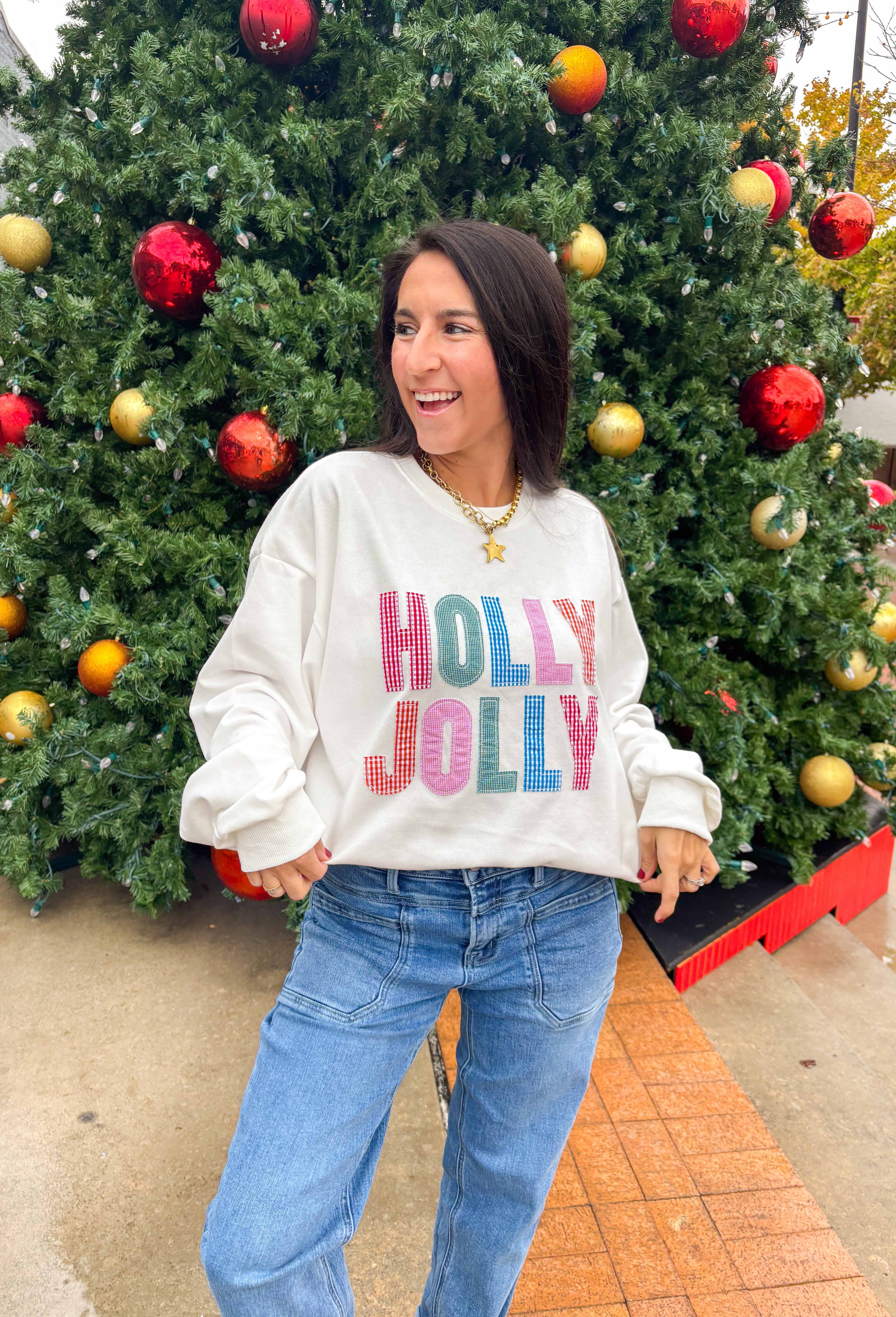 Stay merry and bright this season in the “Holly Jolly” pullover by Main Strip! This soft white lightweight sweatshirt features colorful gingham lettering—each letter a unique mix of festive color and pattern—outlined with white stitching for a playful holiday touch. Cozy and cheerful, it’s the perfect piece for decking the halls, sipping cocoa, or simply spreading a little Christmas joy.
