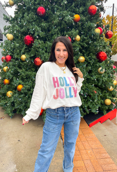 Stay merry and bright this season in the “Holly Jolly” pullover by Main Strip! This soft white lightweight sweatshirt features colorful gingham lettering—each letter a unique mix of festive color and pattern—outlined with white stitching for a playful holiday touch. Cozy and cheerful, it’s the perfect piece for decking the halls, sipping cocoa, or simply spreading a little Christmas joy.