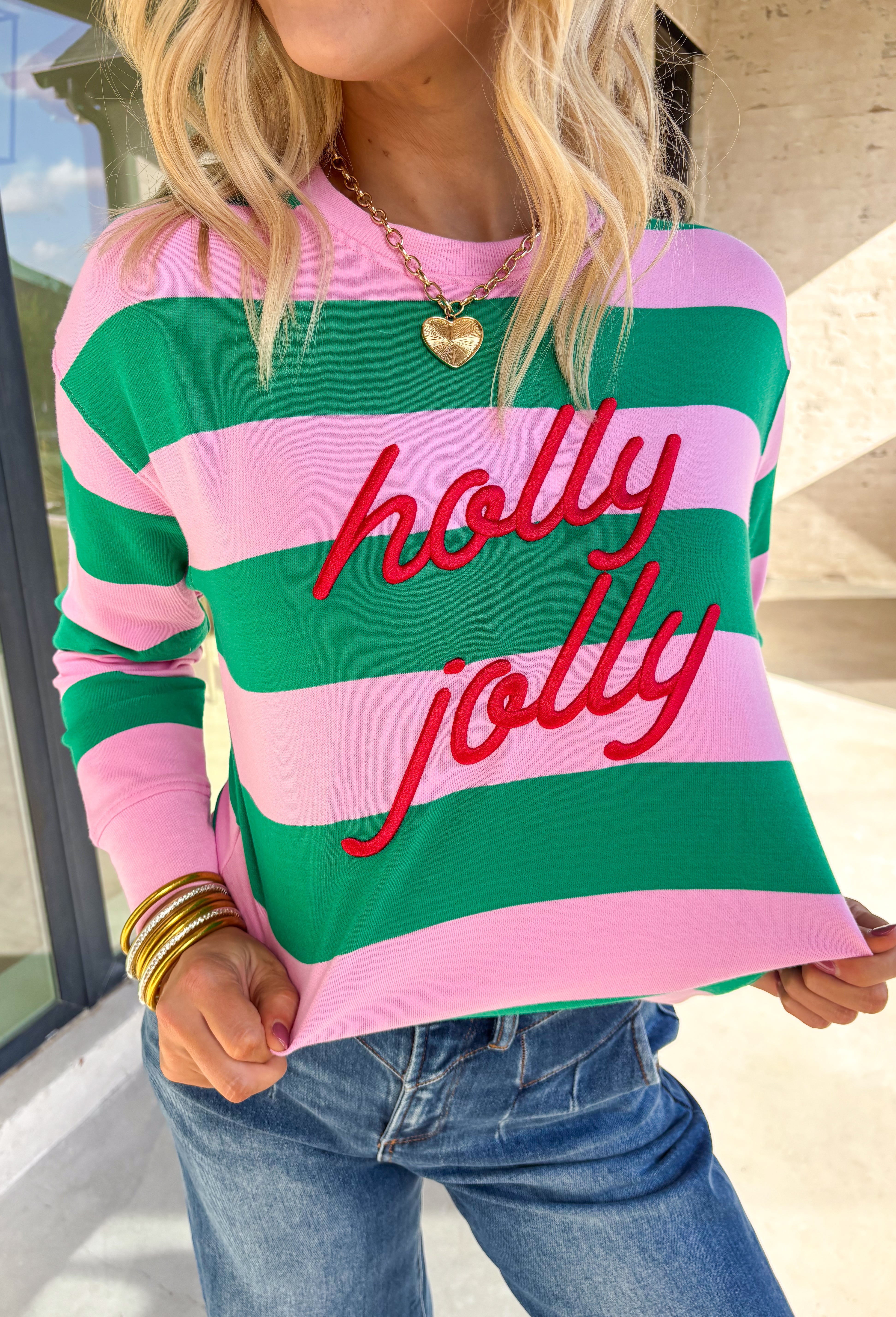 Bring a little merry to your winter wardrobe with this playful “Holly Jolly” pullover by Shiraleah! Designed in pink and green stripes with festive red embroidery across the front, this cozy sweatshirt is equal parts cute and comfortable. Whether you’re wrapping gifts, sipping cocoa, or heading to a holiday get-together, this cheerful piece keeps the spirit bright all season long.