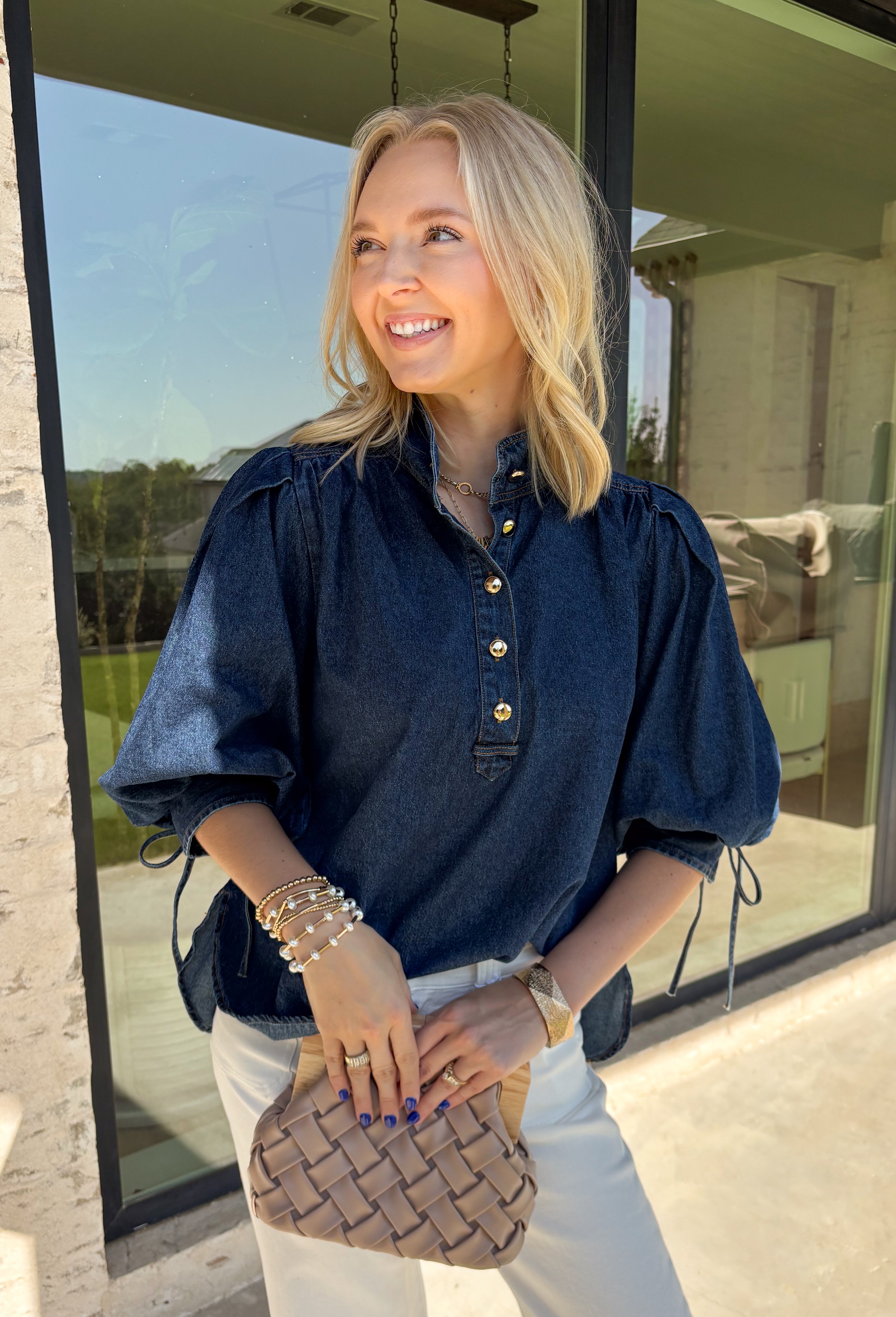 A classic denim top is a wardrobe staple, and this beautifully detailed top from Entro is one you'll wear on repeat. Designed in a rich dark wash denim, this timeless piece features a gold button-front design that makes it easy to style for any occasion. The ¾ puff sleeves add a feminine touch, while the self-tie cuffs create a charming finishing detail.