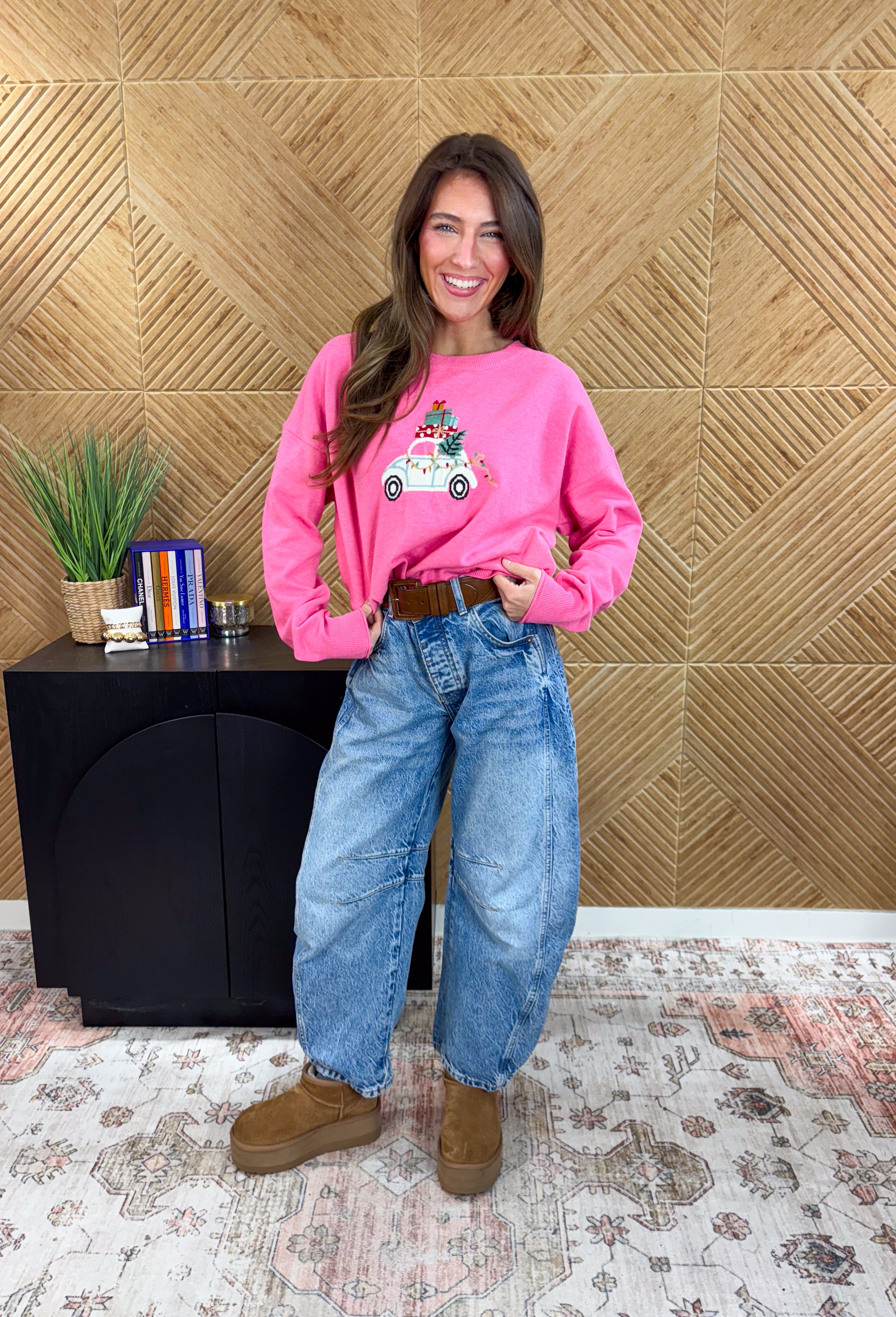 Bring the festive fun with this adorable pink holiday sweater by Sunday Edition! Featuring a white slug bug design complete with a Christmas tree hanging out the back, presents stacked on top, and colorful string lights along the side, this playful knit captures all the magic of the season. Soft, cozy, and full of charm, it’s the perfect sweater for cookie decorating, holiday parties, or any moment that needs a little extra cheer.