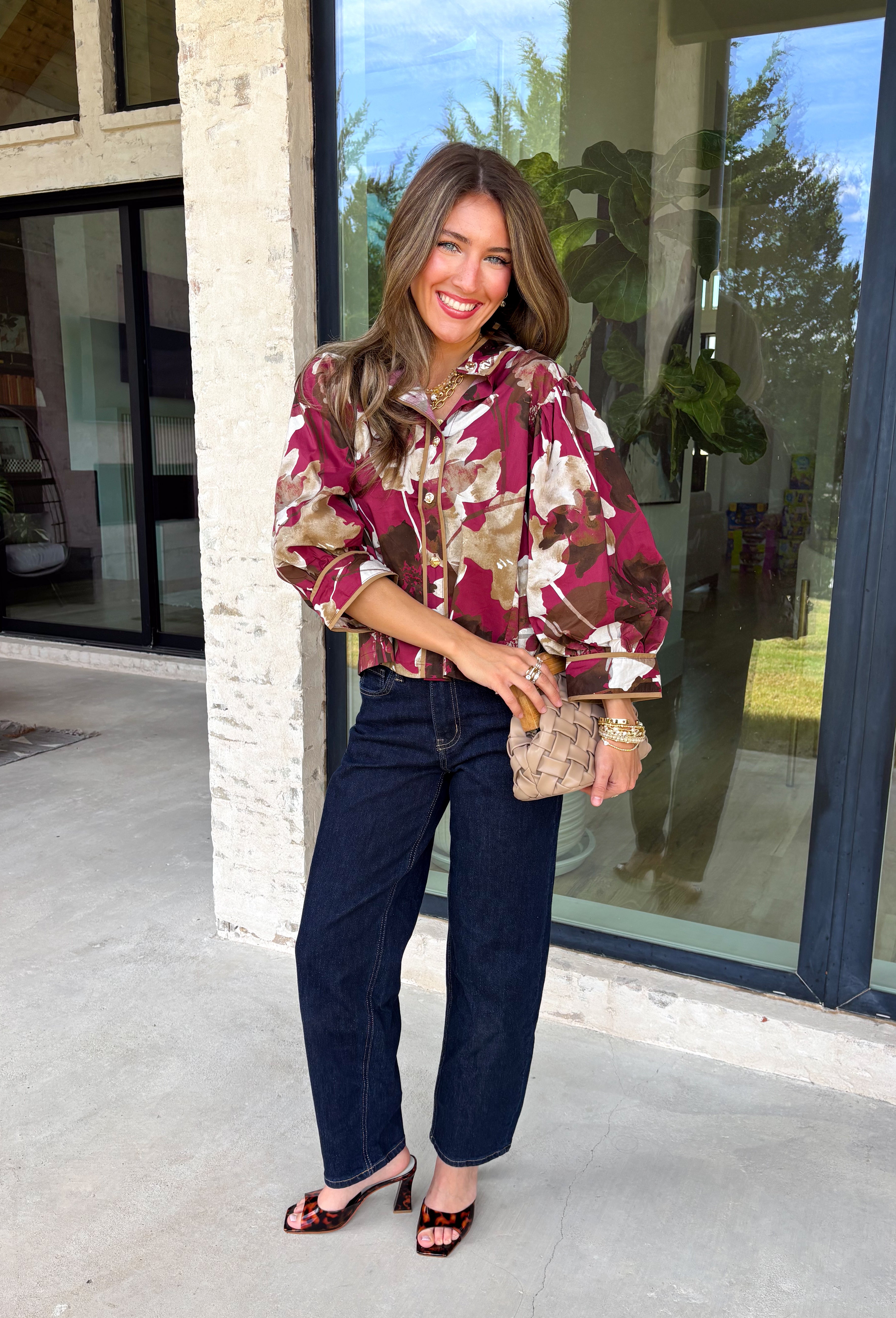 Deep merlot brings a rich seasonal feel to this floral top from Entro. The neutral floral print softens the bold background with warm, easy-to-style shades that fit beautifully into a late-fall wardrobe. A high neckline and button-front closure give the top a classic look, while contrast trim adds another eye-catching detail. The ¾ puff sleeves are finished with buttoned cuffs, and gathering along the back yoke adds subtle shape and movement. 