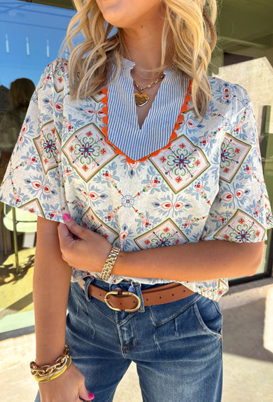 Bright, playful, and made for spring days, this off-white short sleeve top by Voy is an instant mood booster. Featuring a colorful floral print with pops of light blue, green, pink, and red, it brings the perfect burst of color to your everyday lineup. Light blue and white striped detailing along the top adds a fun contrast, while the orange rickrack trim gives it the cutest vintage-inspired finish. Made from breathable cotton, this top is easy to wear and effortless to style all season long.