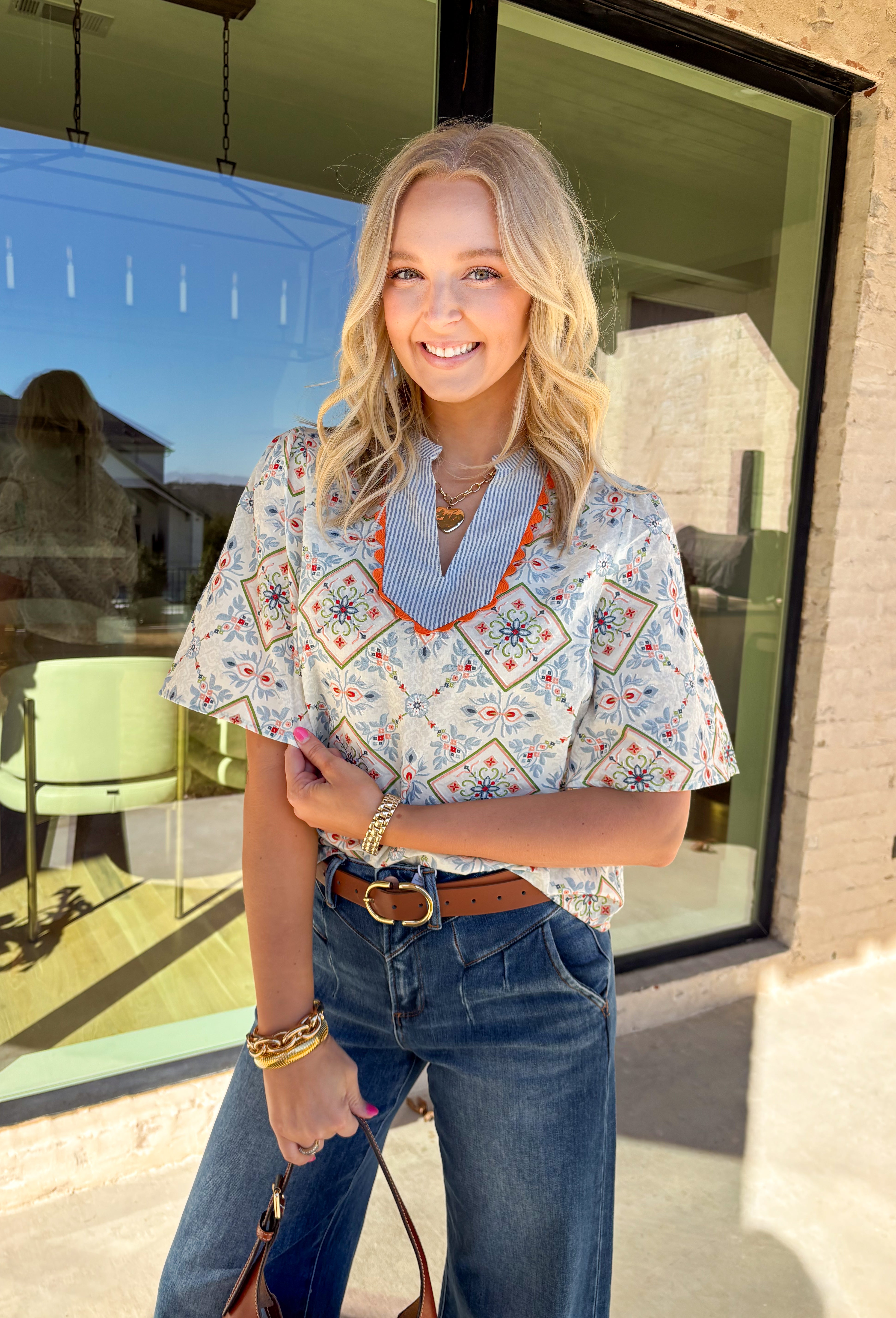 Bright, playful, and made for spring days, this off-white short sleeve top by Voy is an instant mood booster. Featuring a colorful floral print with pops of light blue, green, pink, and red, it brings the perfect burst of color to your everyday lineup. Light blue and white striped detailing along the top adds a fun contrast, while the orange rickrack trim gives it the cutest vintage-inspired finish. Made from breathable cotton, this top is easy to wear and effortless to style all season long.