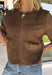 Elevate your autumn wardrobe with a top that's equal parts sophisticated and effortlessly wearable! Crafted from buttery-soft chocolate brown faux suede, this elevated piece brings rich texture and timeless style to any outfit. The standout gold horse bit details on the front pockets add an elegant equestrian-inspired touch, while the sleek back zipper closure creates a polished finish.