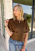 Elevate your autumn wardrobe with a top that's equal parts sophisticated and effortlessly wearable! Crafted from buttery-soft chocolate brown faux suede, this elevated piece brings rich texture and timeless style to any outfit. The standout gold horse bit details on the front pockets add an elegant equestrian-inspired touch, while the sleek back zipper closure creates a polished finish.